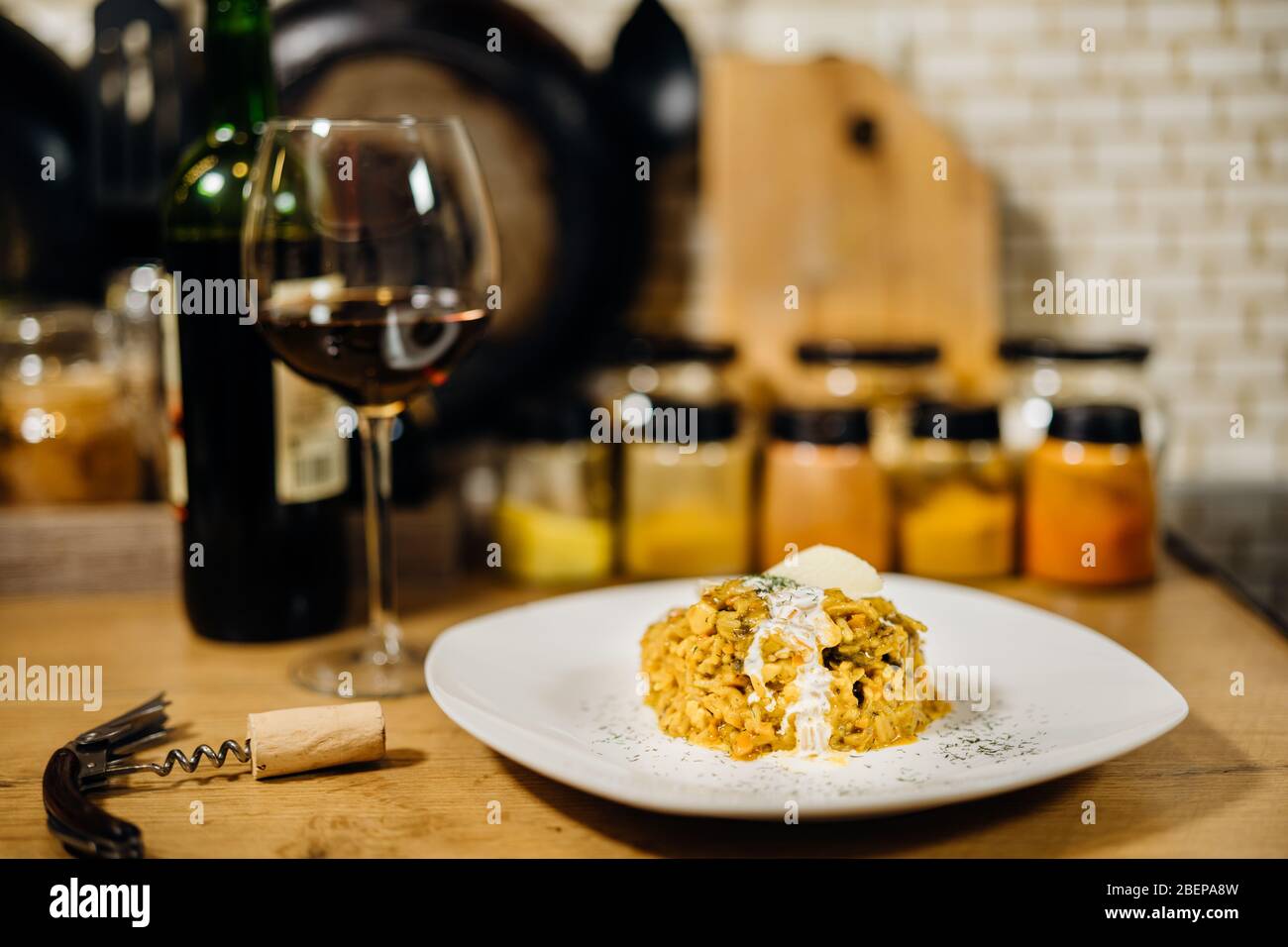 Gelbes Kurkuma-Risotto mit wilden Steinpilzen Platte mit Rotwein serviert.Safranreis mit Parmesan-Käse.Italienische traditionelle Rezepte mit Wein Stockfoto