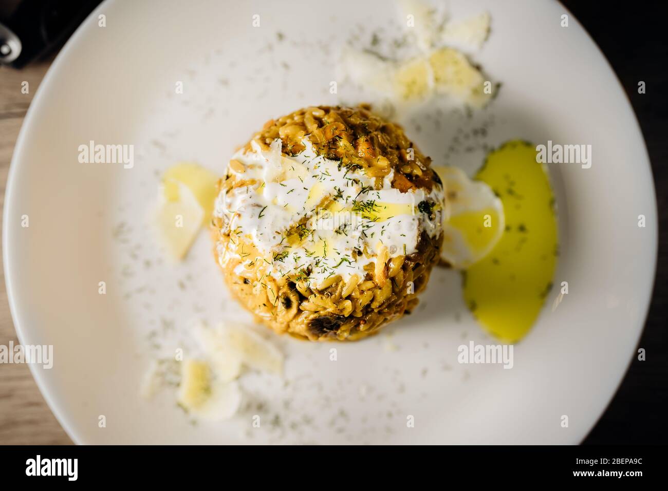 Gelbes Kurkuma-Risotto mit wilden Steinpilzen Platte serviert mit Rotwein.Safranreis mit Parmesan-Käse.Italienische traditionelle Rezepte aus nächster Nähe. Stockfoto