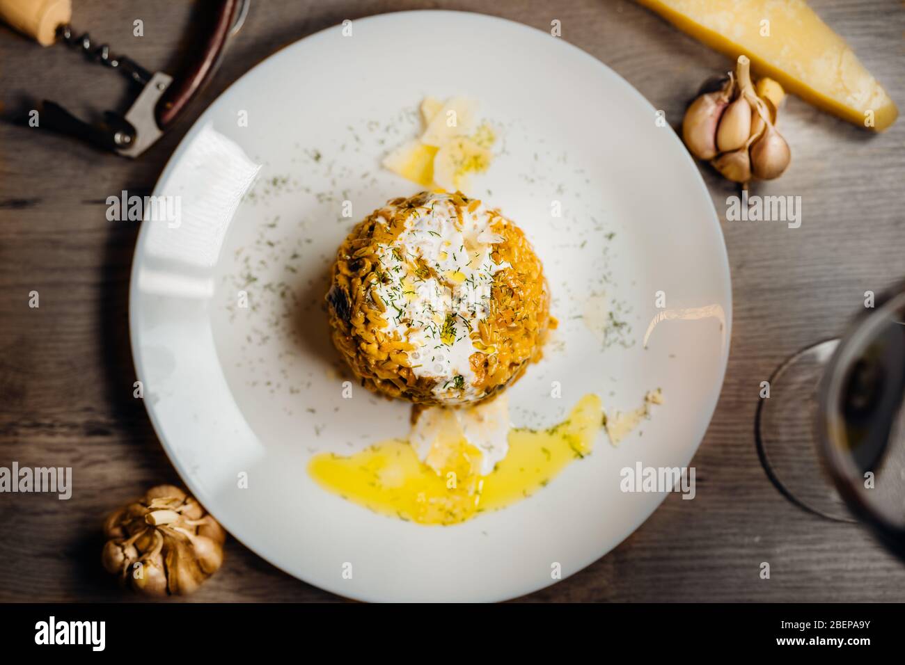 Gelbes Kurkuma-Risotto mit wilden Steinpilzen Platte mit Rotwein serviert.Safranreis mit Parmesan-Käse.Italienische traditionelle Rezepte mit Wein Stockfoto