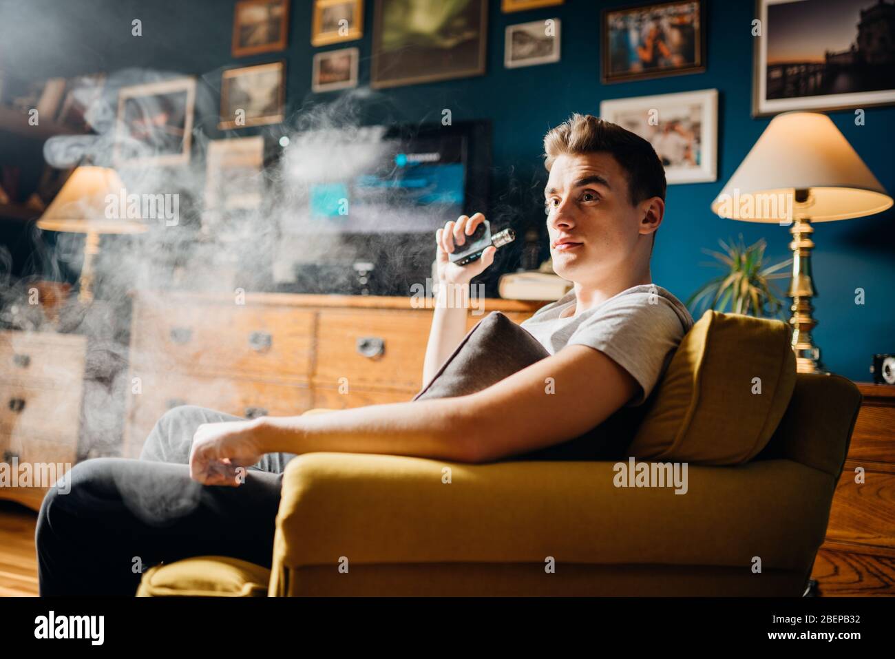 Junger Mann inhalieren eines Dampfes mit elektronischen Zigarette.Vape Geschmack flüssige Chemikalien.Eltern Verwendung von E-Zigaretten in der Heimat.Rauchen und Dampfen negativ Stockfoto