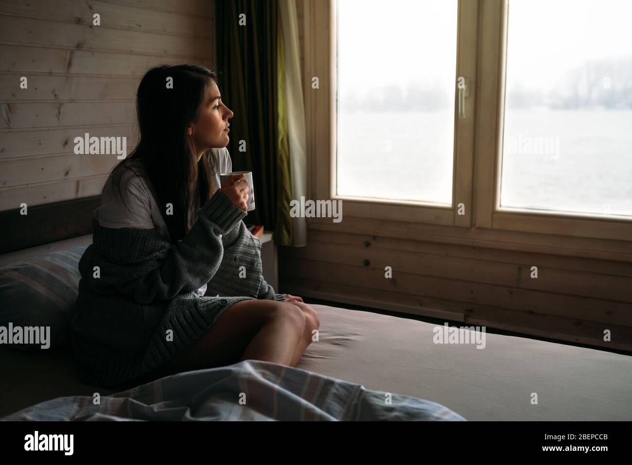 Junge Frau zu Hause zu bleiben Kaffee / Tee trinken, Blick durch das Fenster.Starting den Tag, Morgen Ritual.Quaratine Selbstisolierung concept.Worried wom Stockfoto