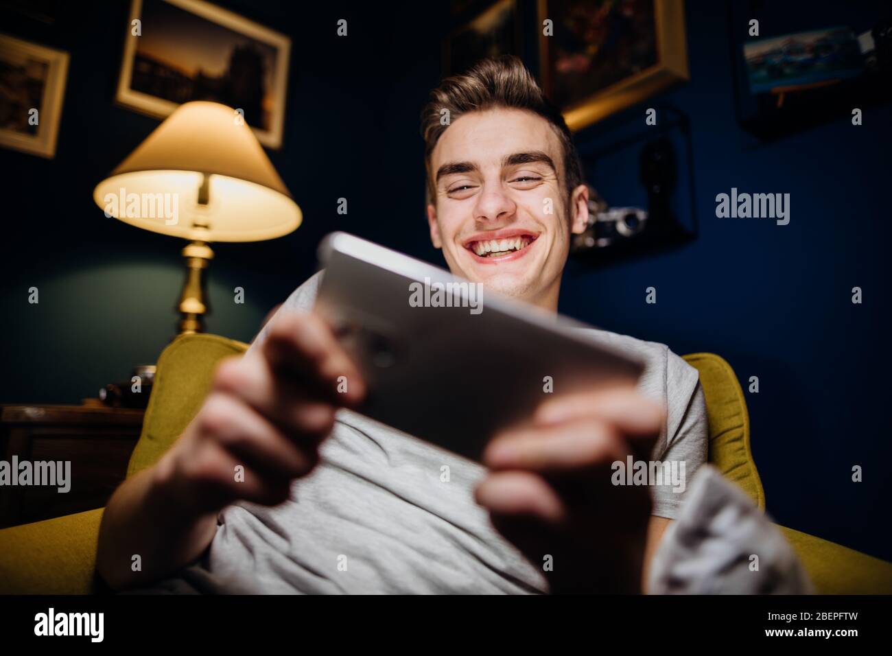 Lächelnder Jugendlicher spielt Videospiele auf Smartphone.Abstrakte virtuelle Realität Gaming-Welt.Internet-Glücksspiel.Zeit zu Hause allein.Gaming unterhalten Stockfoto