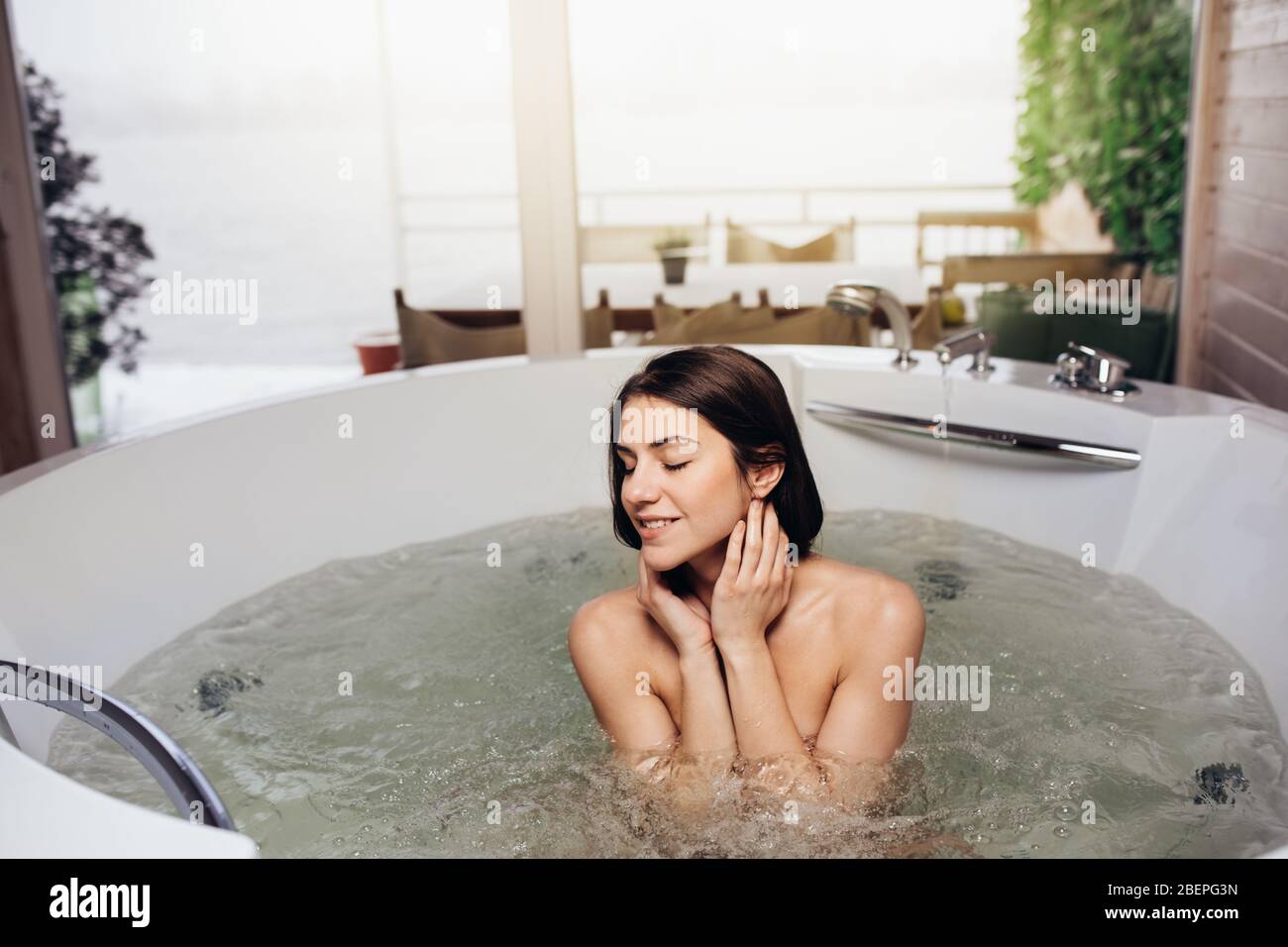 Frau zu Hause im Whirlpool Bad Ritual entspannen.Spa Tag Moment im modernen Bad drinnen Jacuzzi-Wanne.Freizeit Aktivität.Selbstpflege.gute persönliche Hygiene Stockfoto