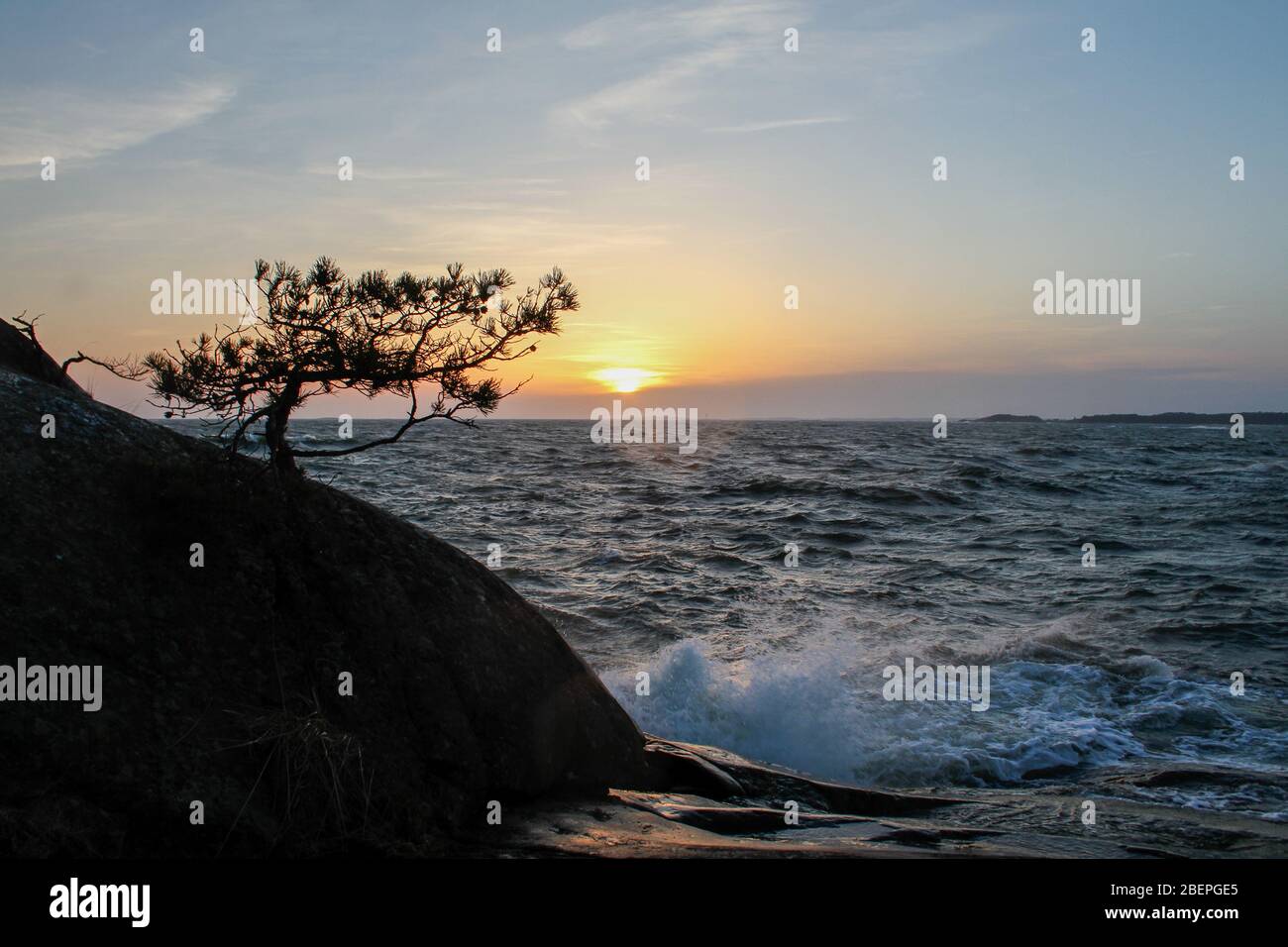 Die Wellen treffen bei Sonnenuntergang auf die Klippe Stockfoto