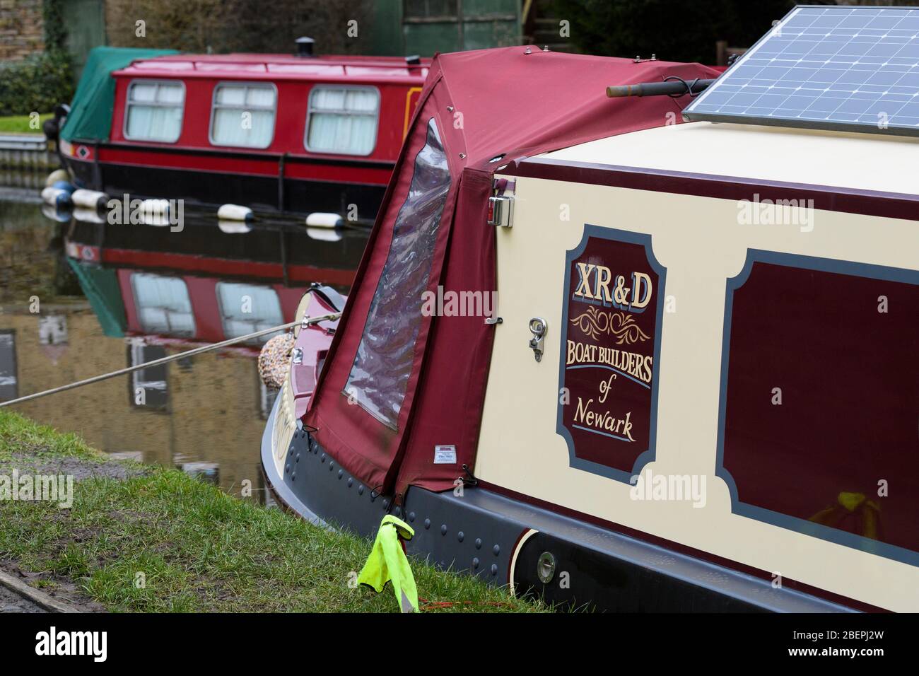 Canal schmale Boote (Bug von 1 Boot) vertäut, Reflexionen, Wasser, Solarpanel, Festmacherseil, Abdeckung - Leeds-Liverpool Canal, Skipton, Yorkshire England UK Stockfoto