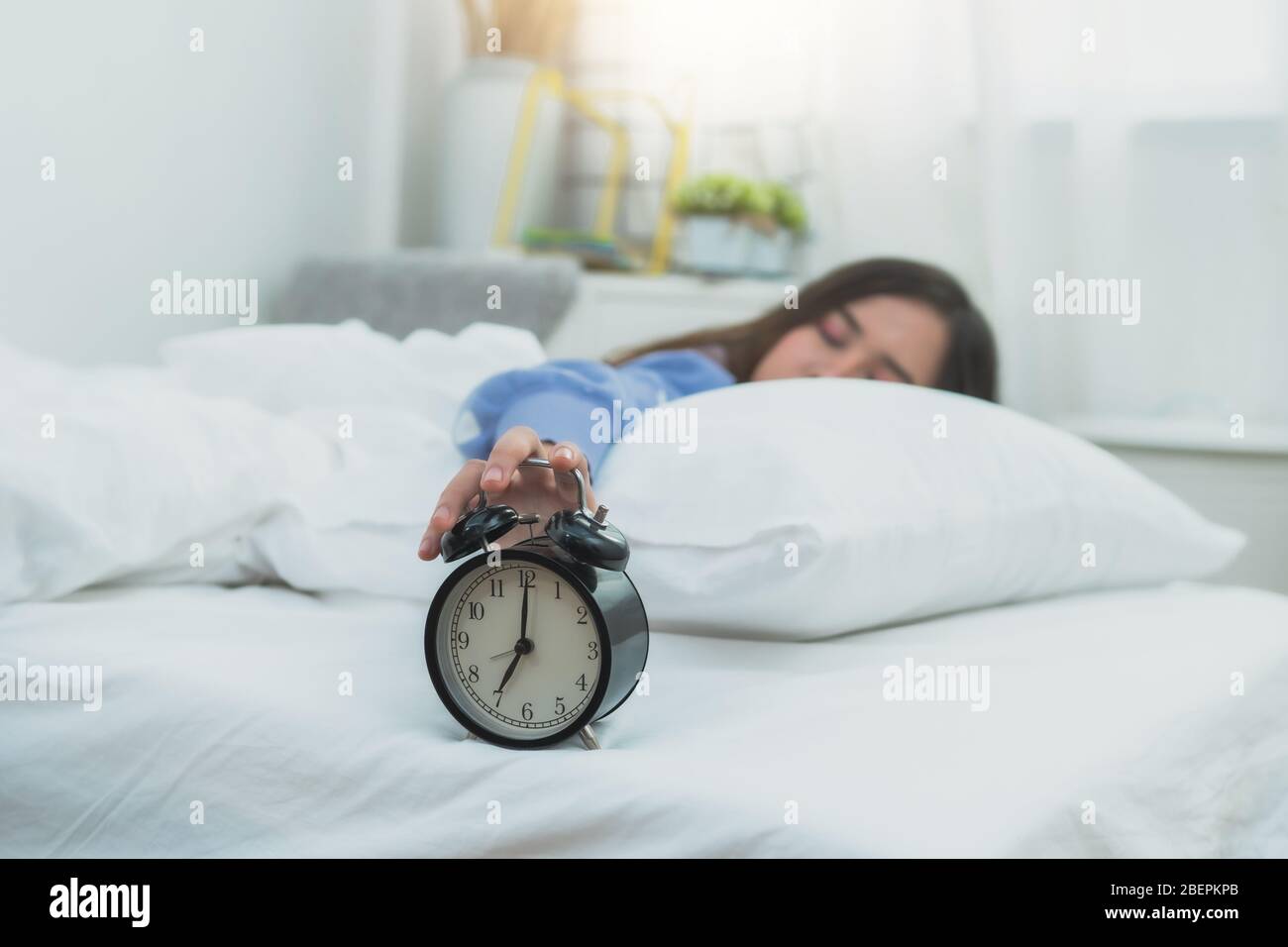 Frau Hand Touch Wecker auf dem Bett, faul und Ruhezeit auf Urlaub Konzept Stockfoto