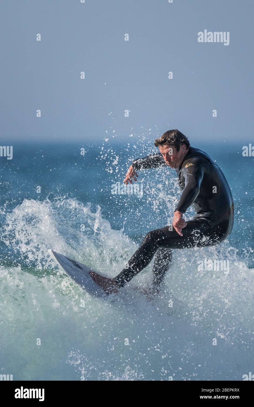 Ein reifer männlicher Surfer, der eine Welle bei Fistral in Newquay in Cornwall reitet. Stockfoto