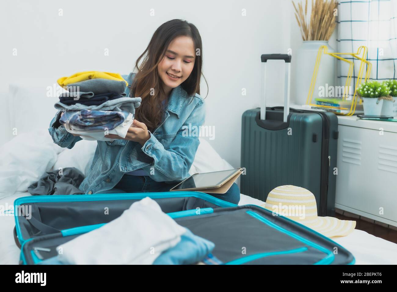 Vorbereitung und Reiseplanung auf Urlaubskonzept, Thai und Asien glücklich Frau packen Kleidung in Gepäck Koffer Tasche auf dem Bett zu reisen Stockfoto