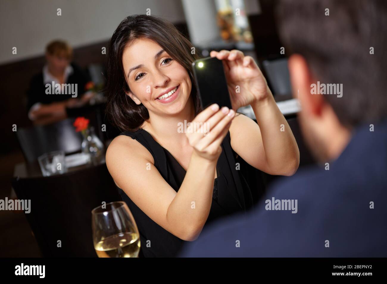 Frau fotografiert ihren Partner mit Handy im Restaurant Stockfoto