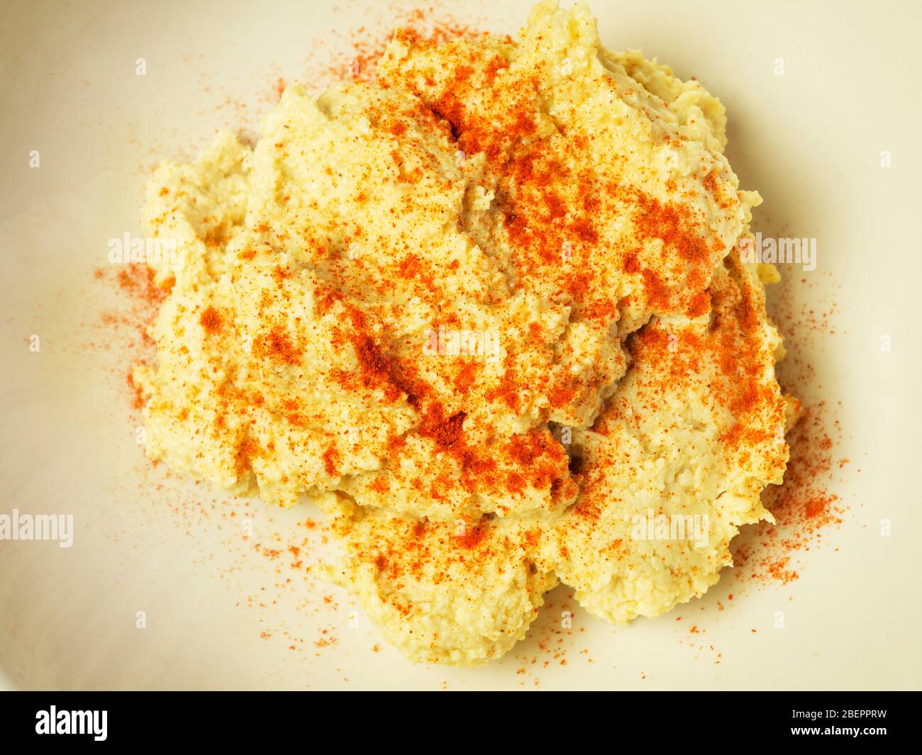 Frisch zubereiteter Hummus aus Kichererbsen Tahini Olivenöl Zitronensaft und Knoblauch mit Paprika bestreut Stockfoto