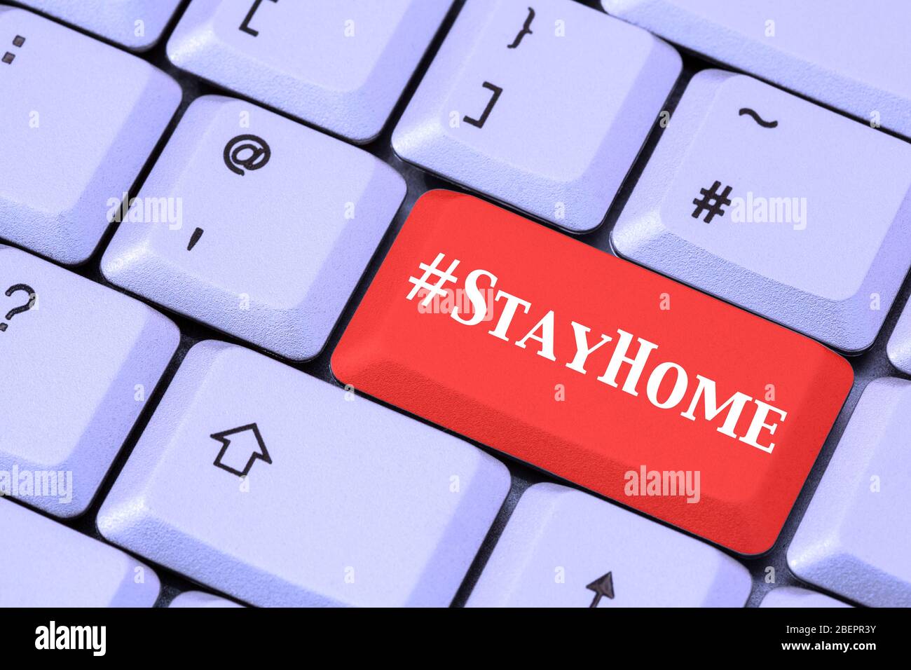 Eine Tastatur mit #StayHome auf einer roten ENTER-Taste. Covid-19 Coronavirus-Pandemie bleibt zu Hause Lockdown-Konzept im April 2020. England, Großbritannien Stockfoto