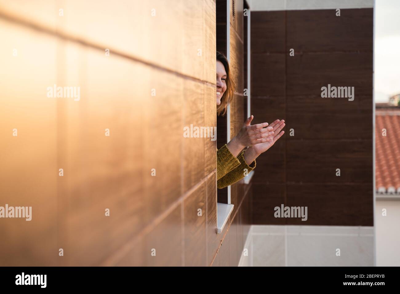 Junge Frau in Quarantäne applaudiert, um Gesundheitsarbeiter zu unterstützen Stockfoto