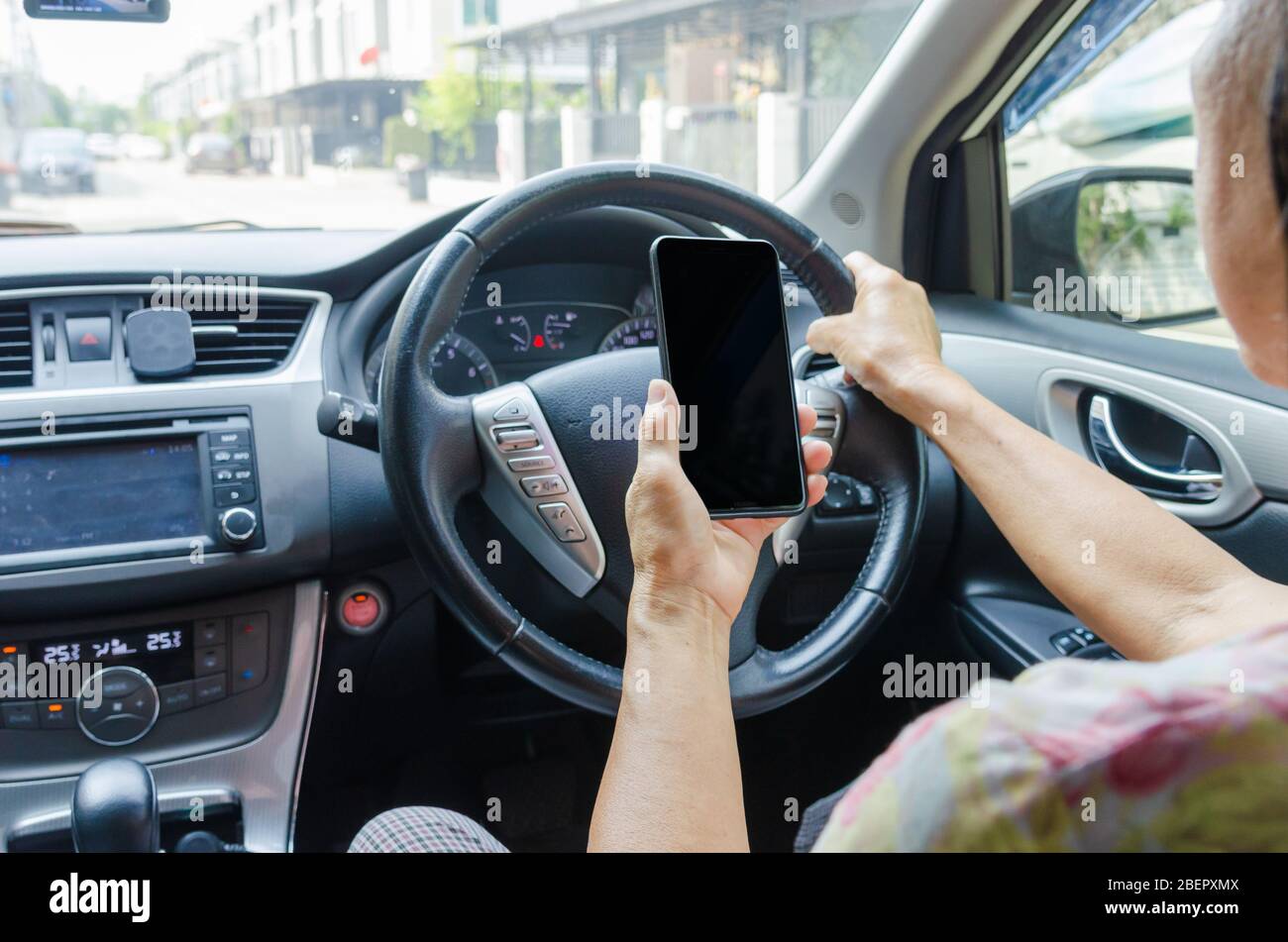 Frauenhand, die ein Mobiltelefon im Auto hält.mit dem Handy im Auto.Clipping Pfad Smartphone. Stockfoto