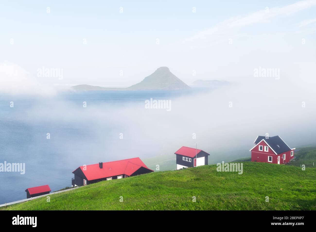 Neblige Morgenansicht eines Hauses mit rotem Dach im Dorf Velbastadur auf der Insel Streymoy, Färöer, Dänemark. Landschaftsfotografie Stockfoto
