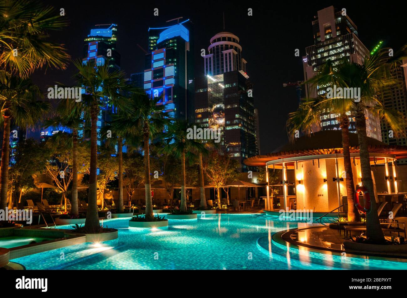 Swimmingpool am Abend mit den nahe gelegenen Gebäuden, die im Shangri-la Hotel Doha beleuchtet werden, jetzt als JW Marriott Marquis City Centre gebrandmarkt. Stockfoto