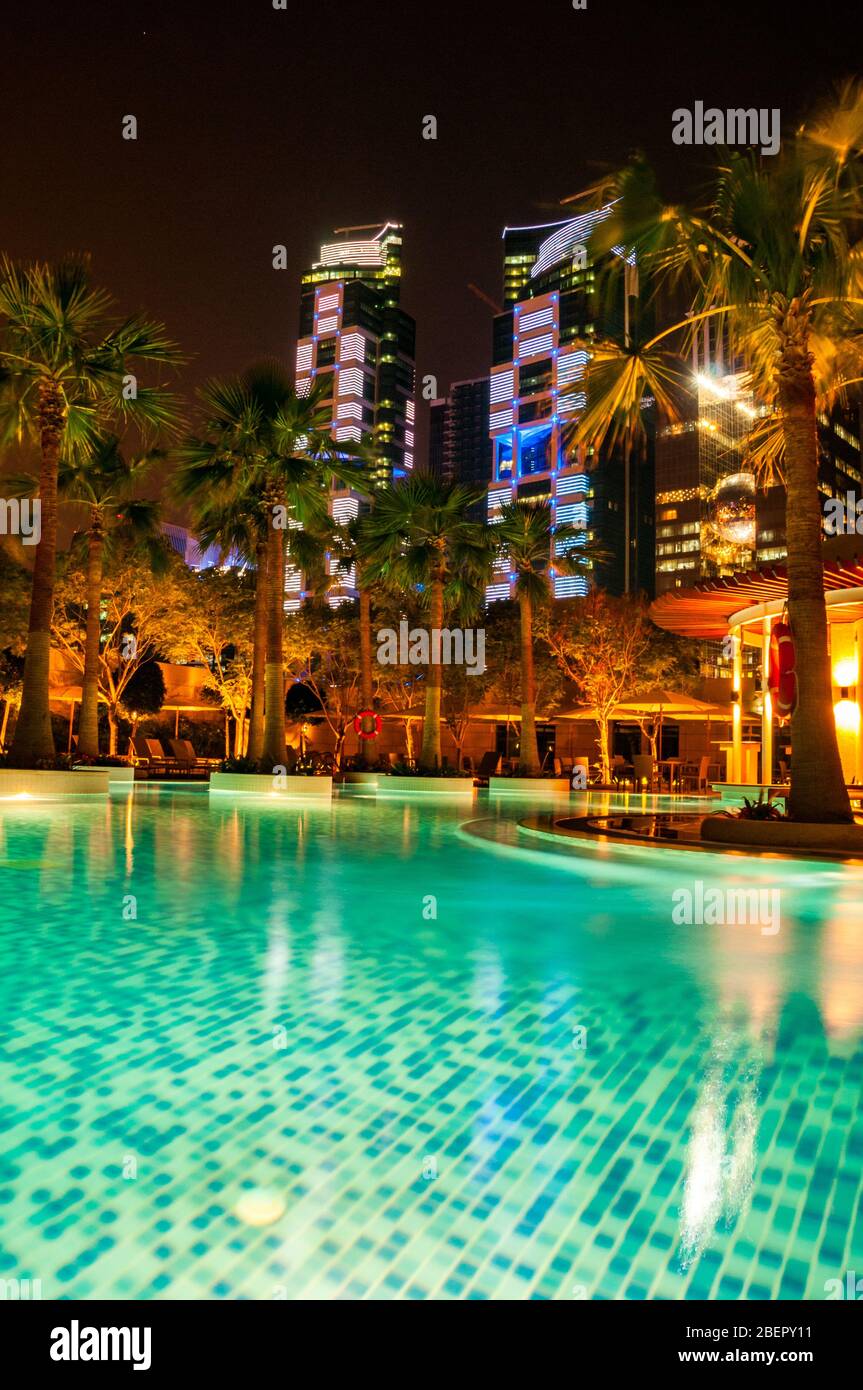 Swimmingpool am Abend mit den nahe gelegenen Gebäuden, die im Shangri-la Hotel Doha beleuchtet werden, jetzt als JW Marriott Marquis City Centre gebrandmarkt. Stockfoto