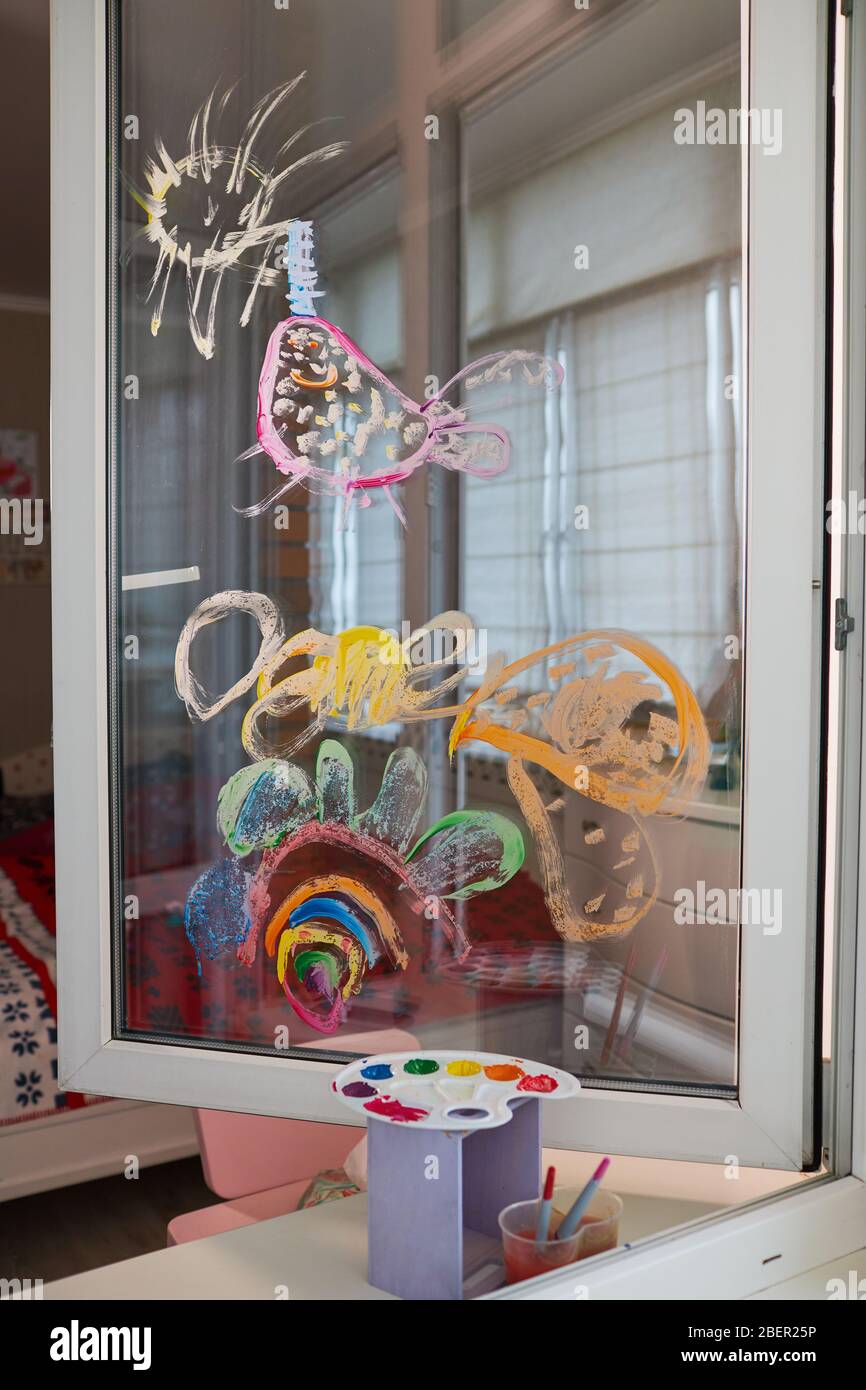 Kinder zeichnen auf dem Glasfenster mit Farben. Das Konzept der Selbstisolierung zu Hause. Junge Künstlerin lernt zeichnen Stockfoto