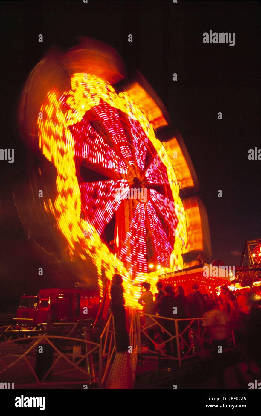 Kirmes. Nachtansicht des rotierenden Riesenrads mit Menschen. Stockfoto