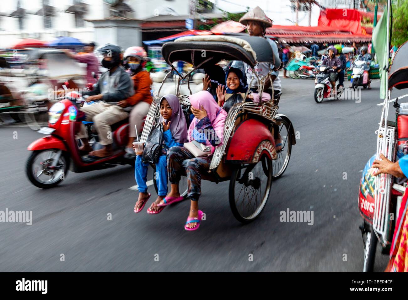 Eine Gruppe indonesischer Kinder, die in EINEM traditionellen Becak (Cycle Rickshaw), Malioboro Street, Yogyakarta, Indonesien reisen. Stockfoto