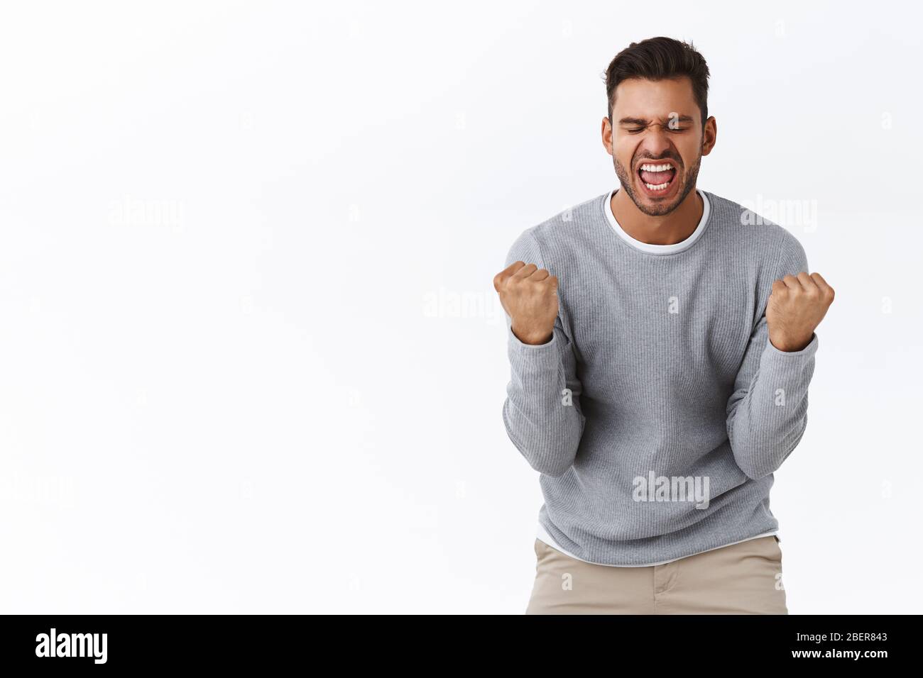 Lebensziele, Gewinn und Erfolgskonzept. Der stattliche Gewinner bringt Begeisterung und Freude zum Ausdruck, wenn er mit übergroßer Freude die geballten Fäuste hochhebt Stockfoto