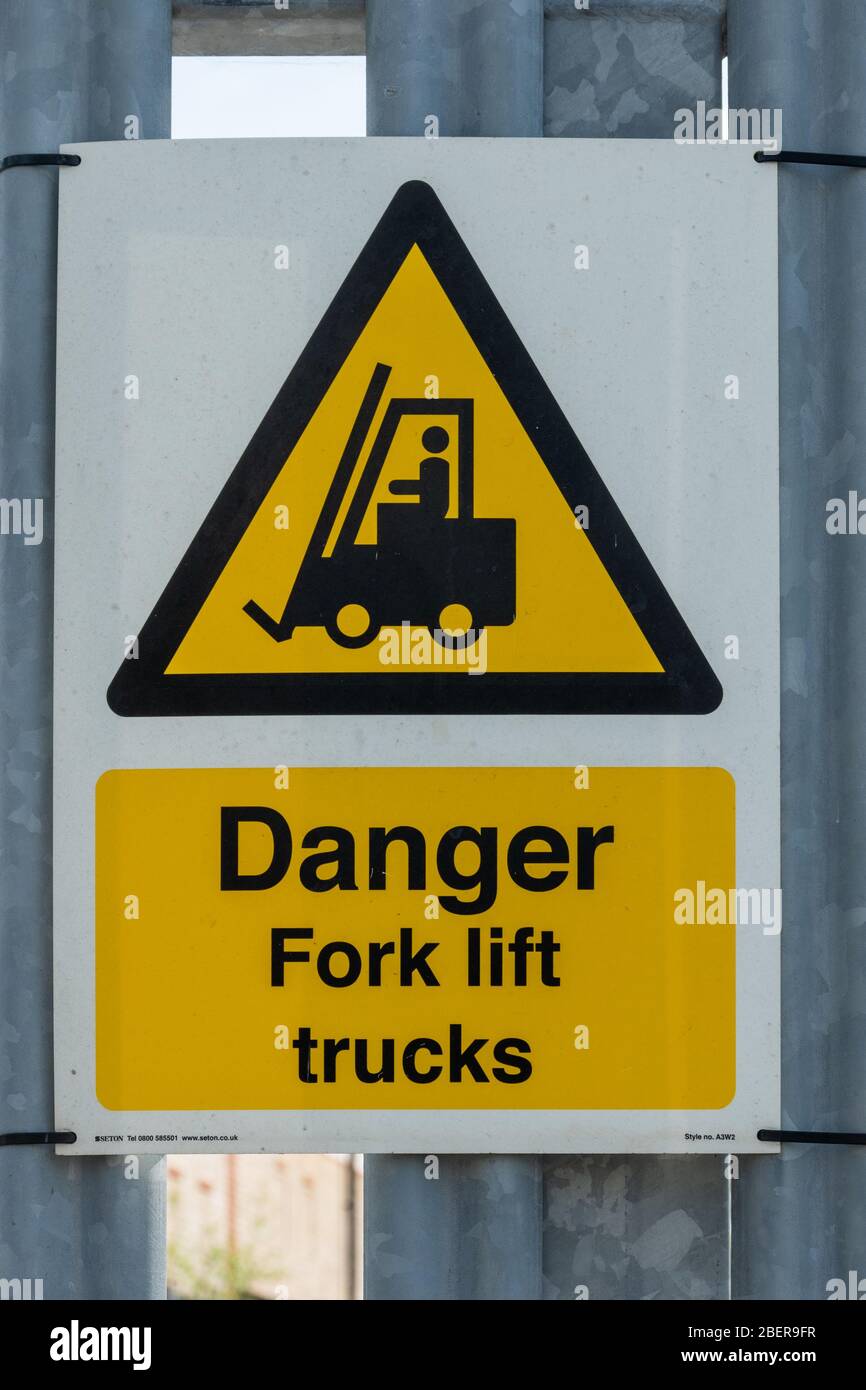 Gefahr Gabelstapler, gelbe dreieckige Warnblinkanlage für Gesundheit und Sicherheit oder Hinweis am Tor eines Industriestandortes, Großbritannien Stockfoto