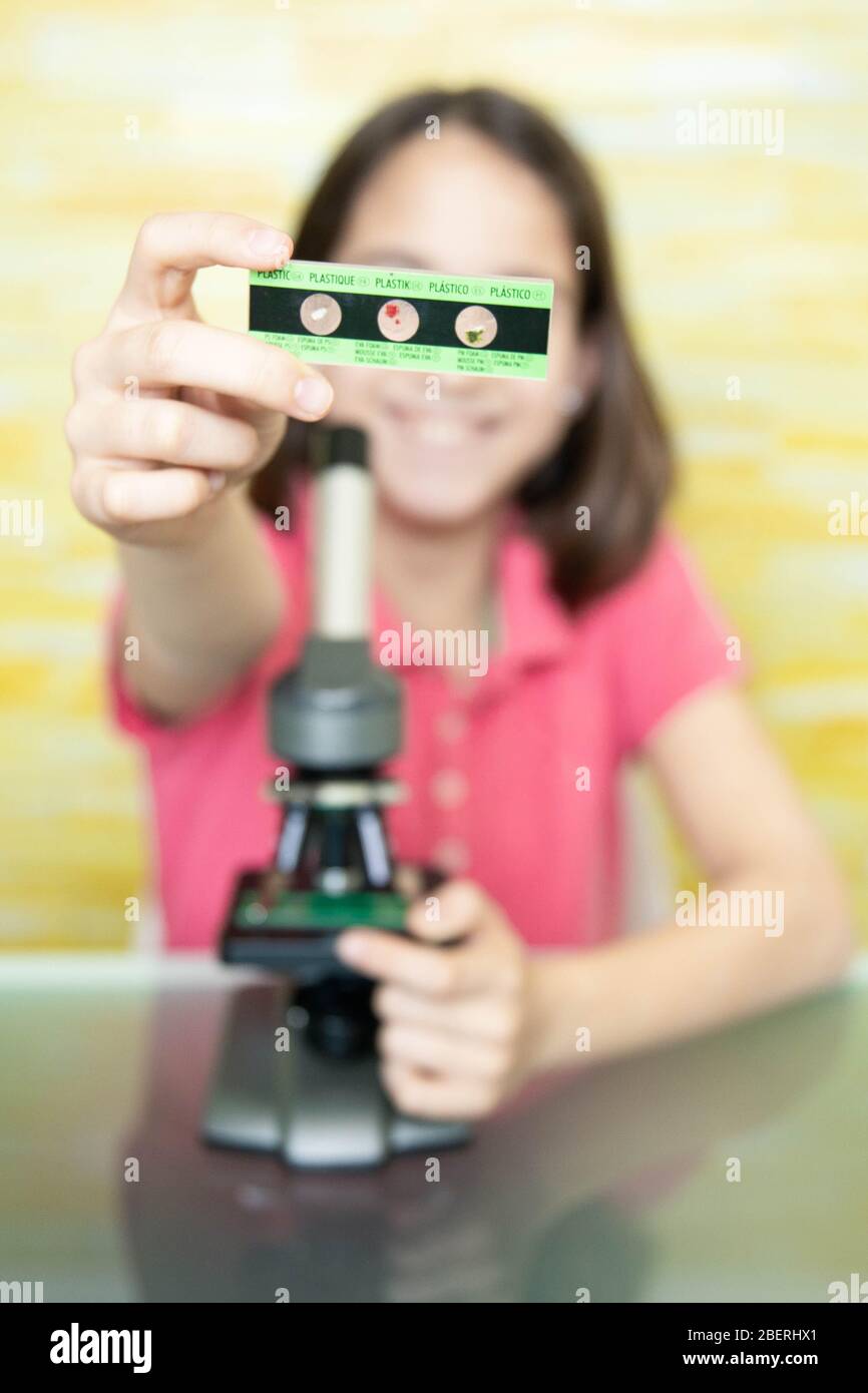 Lächelndes Mädchen zu Hause zeigt das Mikroskop Folie Stockfoto