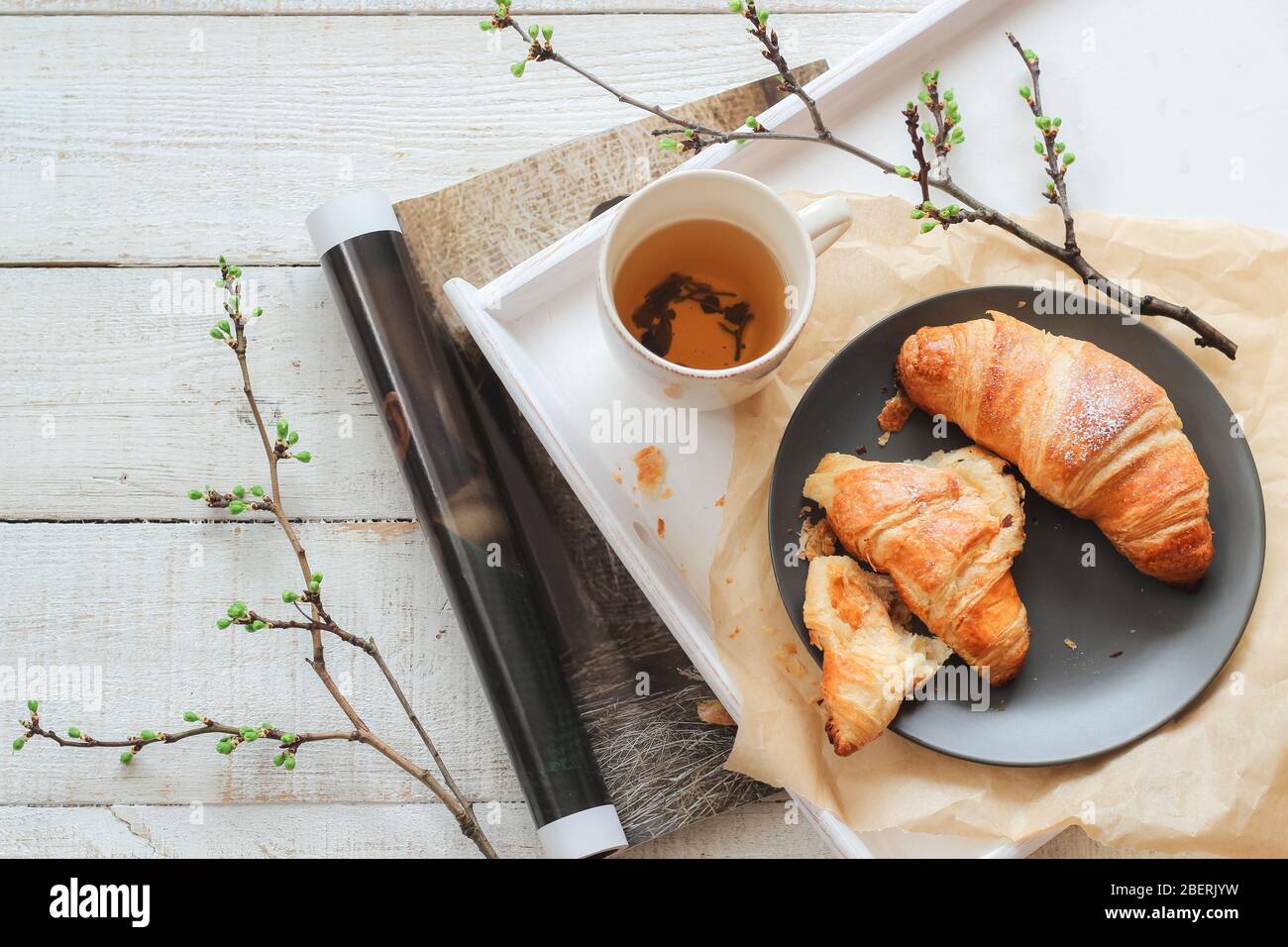 Frische Croissants und eine Tasse Tee zum Frühstück. Helle Stimmung Flatlay Stockfoto