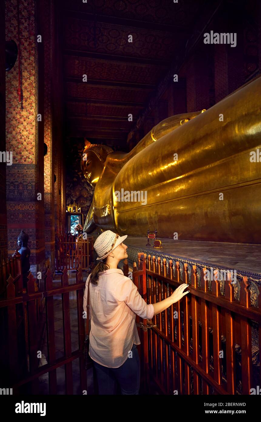Frau Tourist in der Nähe der Statue des Großen Goldenen Buddha im Wat Pho Tempel in Bangkok, Thailand. Symbol für die buddhistische Kultur. Stockfoto