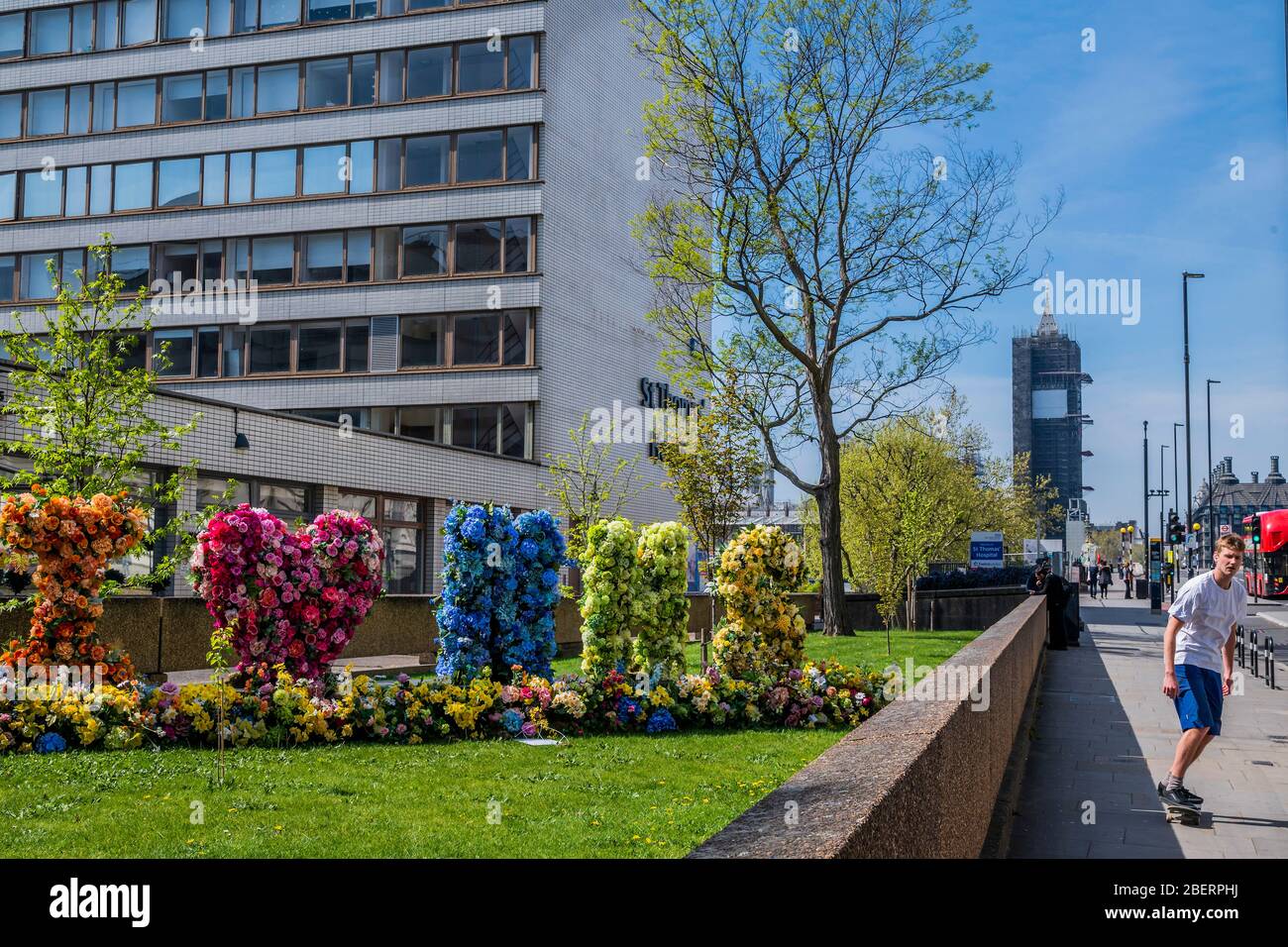 London, Großbritannien. April 2020. Passanten bewundern und fotografieren eine Blumenvererber, die "I Love (Heart) NHS" buchstabiert, vor dem St. Thomas' Hospital - die "Sperre" geht in London wegen des Coronavirus (Covid 19)-Ausbruchs weiter. Kredit: Guy Bell/Alamy Live News Stockfoto