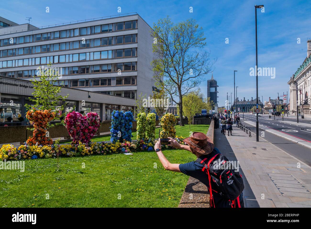 London, Großbritannien. April 2020. Passanten bewundern und fotografieren eine Blumenvererber, die "I Love (Heart) NHS" buchstabiert, vor dem St. Thomas' Hospital - die "Sperre" geht in London wegen des Coronavirus (Covid 19)-Ausbruchs weiter. Kredit: Guy Bell/Alamy Live News Stockfoto