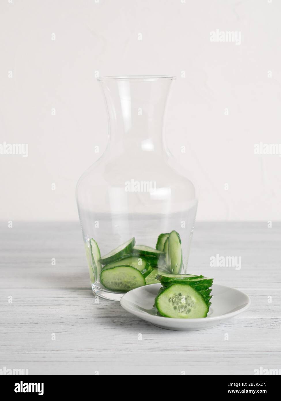 Glas mit Gurkenscheiben innen und Zutaten auf dem Teller für Gurkenwasser Rezept. Hausgemachtes Entgiftungskonzept. Vertikal Stockfoto