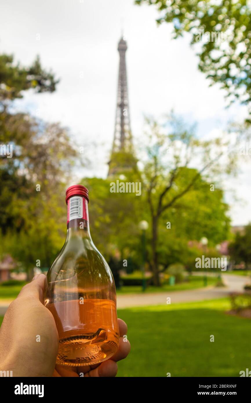 Paris, Frankreich - 9. APRIL 2019: Eifelturm aus einem anderen Blickwinkel. Hand mit einer Flasche Wein, Paris, Frankreich Stockfoto