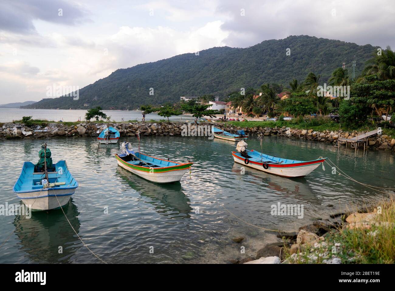 Traditionelle Fischerboote am Pier der Insel Koh Phangan in Thailand bei Sonnenuntergang an einem bewölkten Tag. Stockfoto