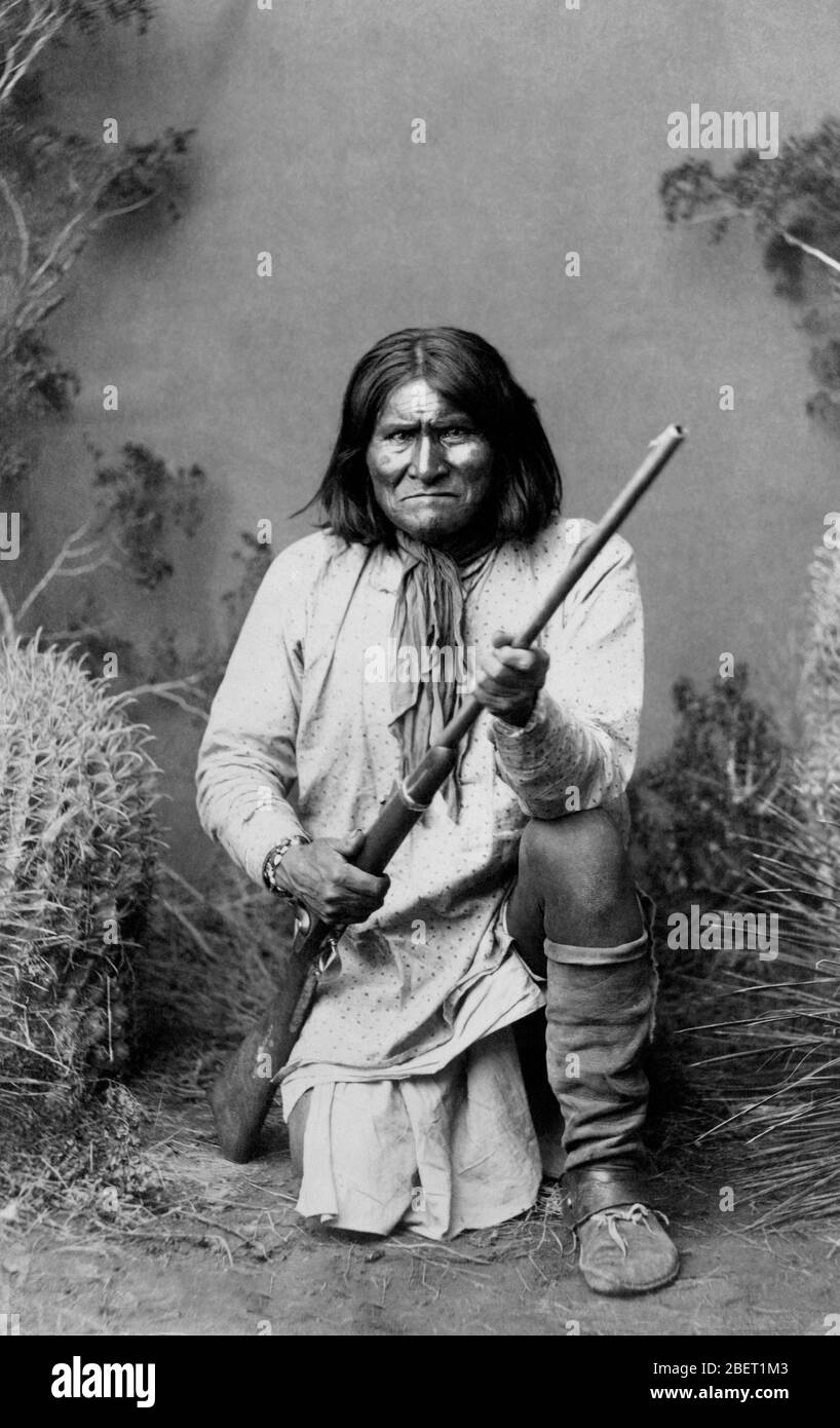 Porträt von Geronimo mit einem Gewehr, als er kniet in 1886. Stockfoto