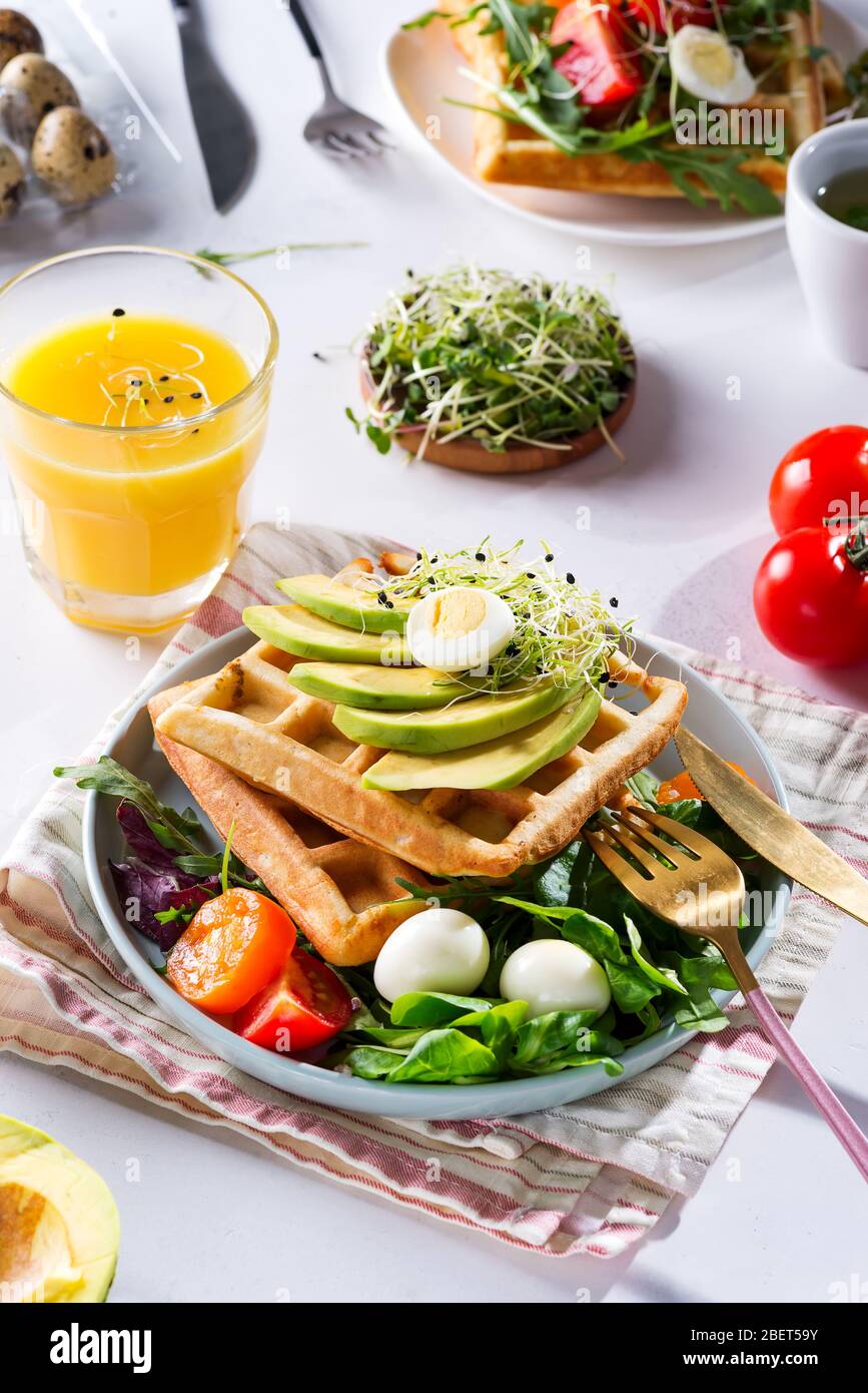 Frühstückszeit. Waffeln mit Salat, Ei, Saft und Avocados zum Frühstück. Blick von oben. Stockfoto