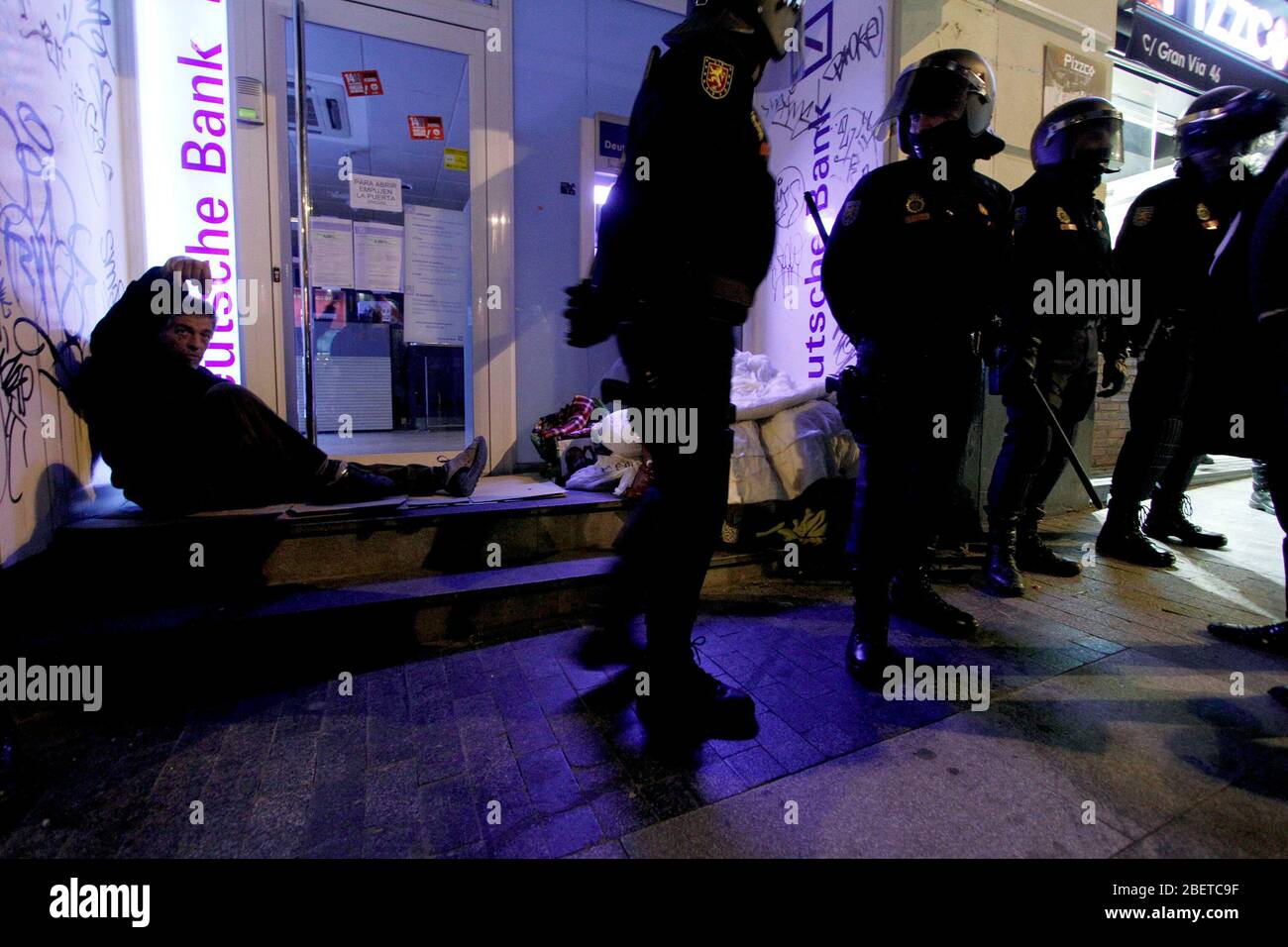 Europäischer Generalstreik.EIN Obdachloser schläft an der Tür eines Bankbüros, umgeben von vielen Mitgliedern der Nationalen Polizei.November 14,2012. (ALTERP Stockfoto