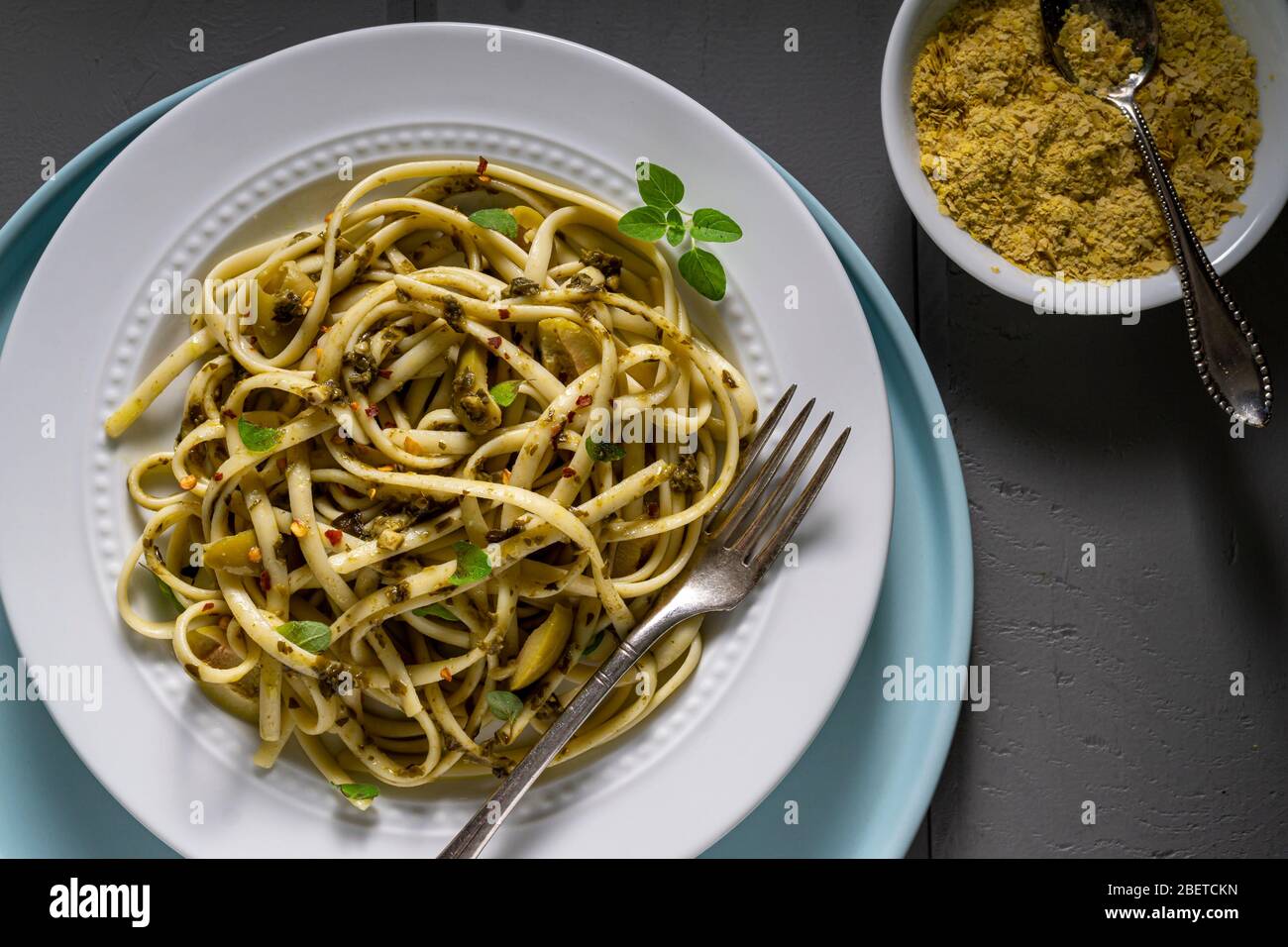 Veganes Nudelgericht. Fettuccine mit Pesto, grünen Oliven, frischem Thymian und Nährhefe. Stockfoto