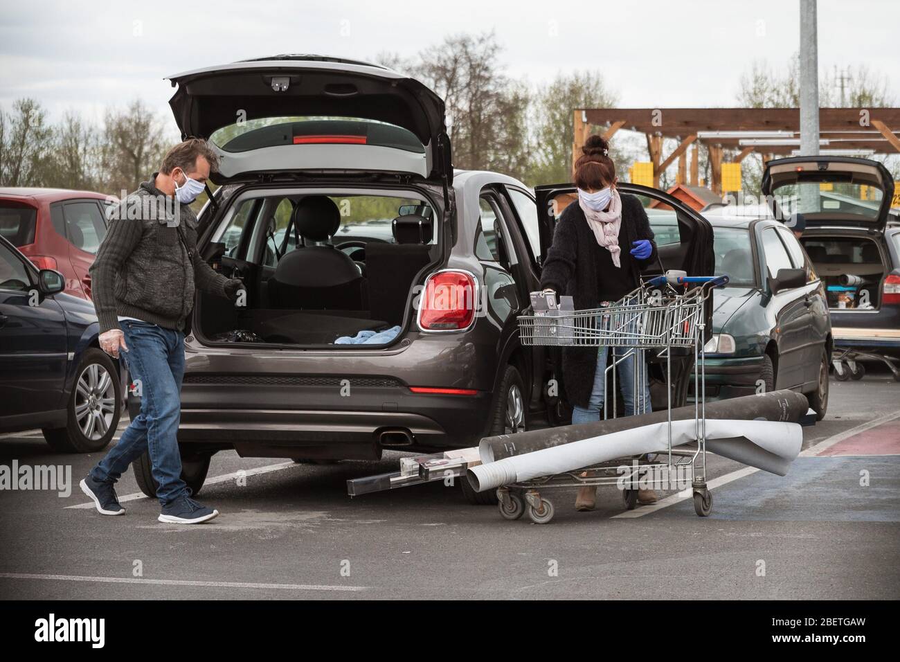 LUBIN, POLEN - 14. APRIL 2020. Mann und Frau laden Einkäufe aus einem Supermarkt in einem Gebäude in den Kofferraum eines Autos. Stockfoto