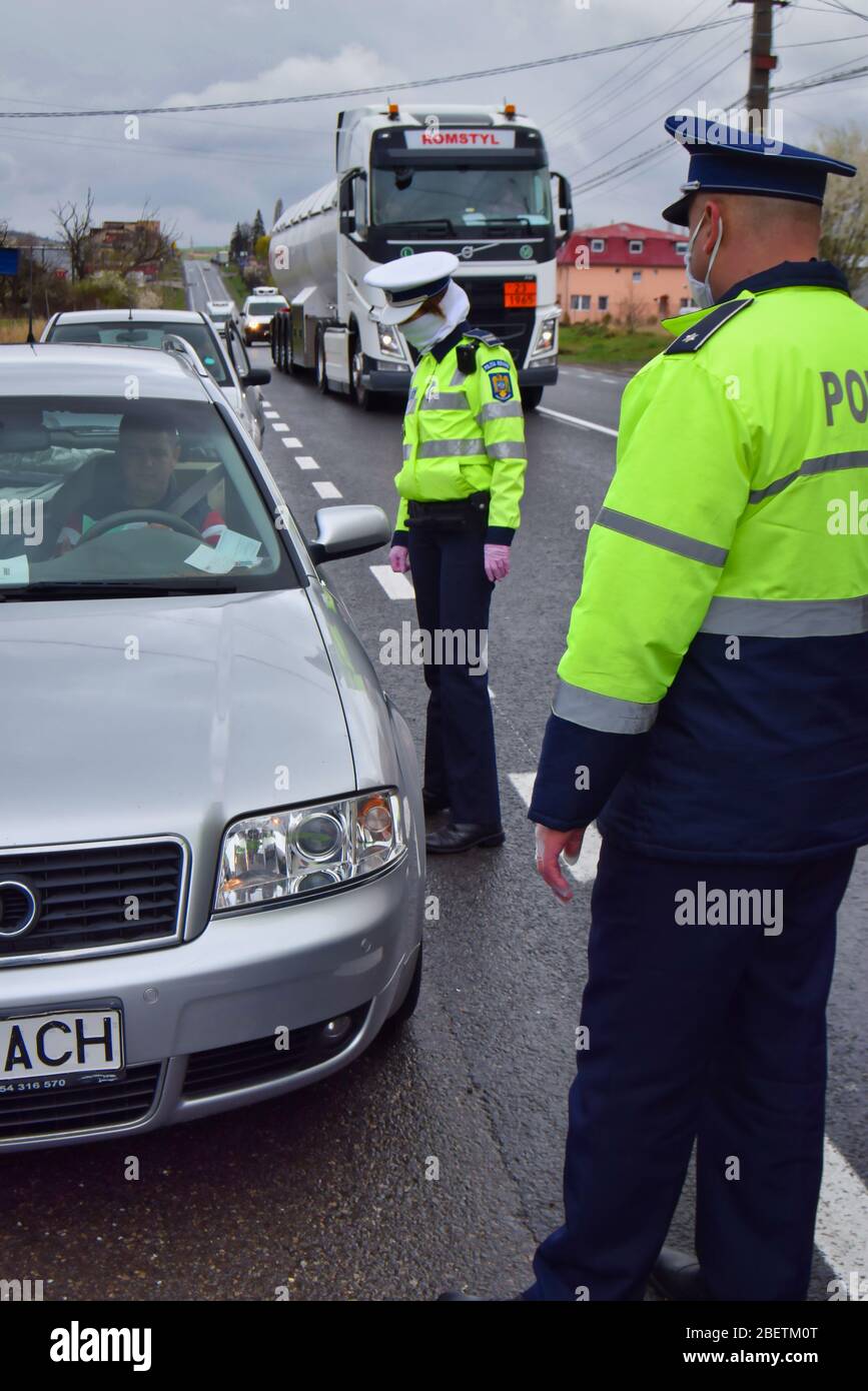 Polizeiagent, Rumänische Verkehrspolizei (Politia Ruiera) mit chirurgischen Handschuhen und Maske halten Autos an, um Führerschein und Papiere zu überprüfen. Covid 19 Stockfoto