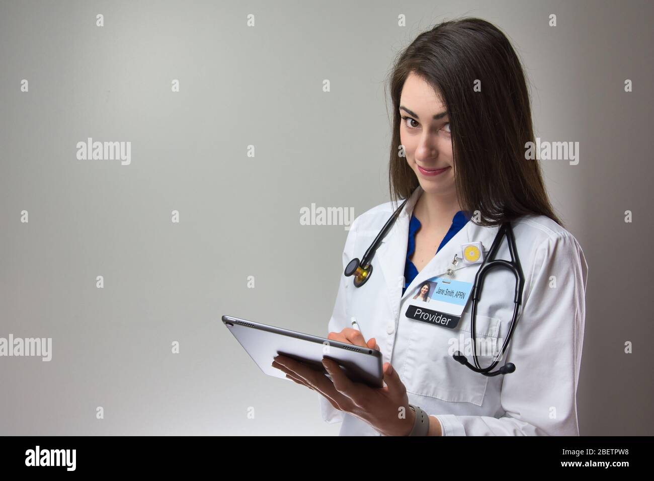 Pflegepersonal macht Notizen auf dem Tablet zur Patientenakte. Weibliche Gesundheitsarbeiter mit Stethoskop und Abzeichen mit Technologie in der Gesundheit bieten Stockfoto