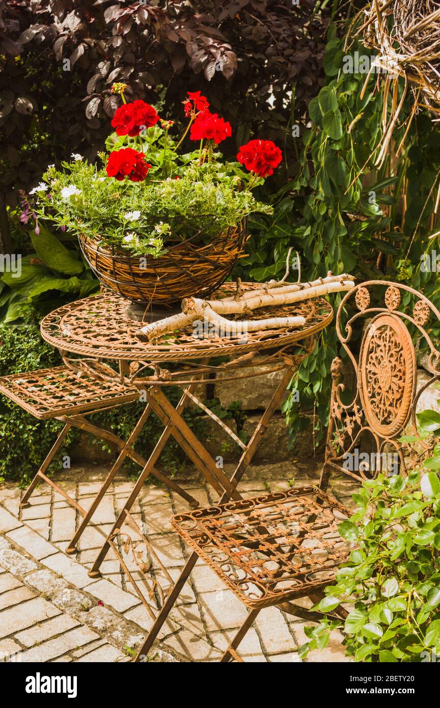 Idyllische Sitzecke im Garten mit Blumenarrangement und Tischstühlen im Bistrostil Stockfoto