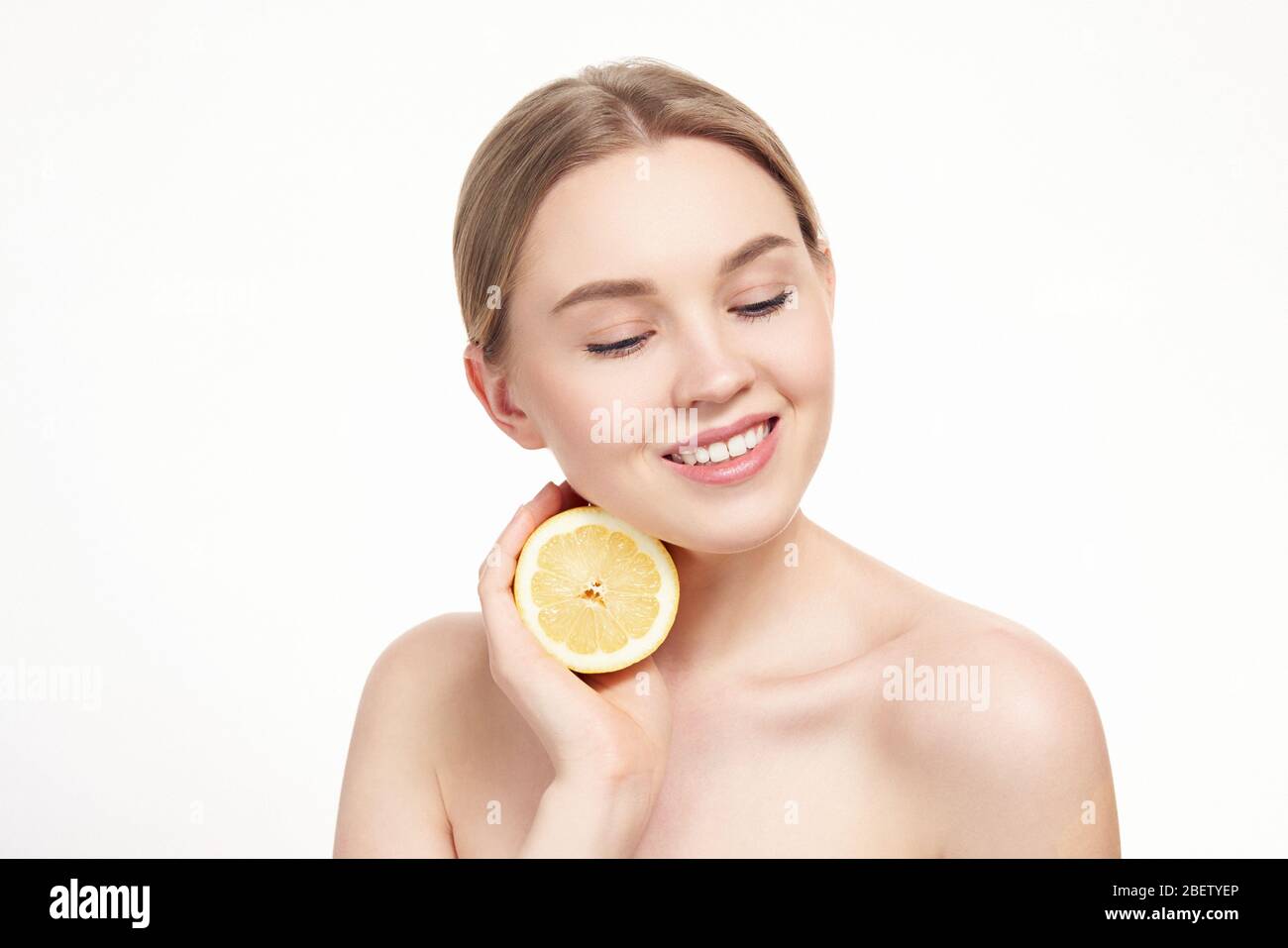 Junge attraktive Mädchen posiert im Studio mit Zitrone. Schönes weibliches Gesicht mit gesunder Haut und Augen. Junge blonde natürliche Frau mit lebendigen Make-up. Ski Stockfoto