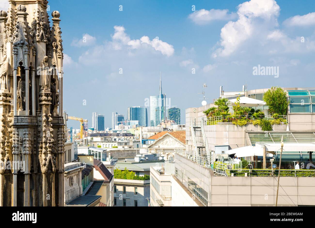 Weiße Marmorstatuen Figuren auf dem Dach des berühmten Duomo di Milano Cathedral und von oben aus Sicht auf die Wolkenkratzer im Stadtzentrum von Mailand mit blauem, himmelweißem Clou Stockfoto