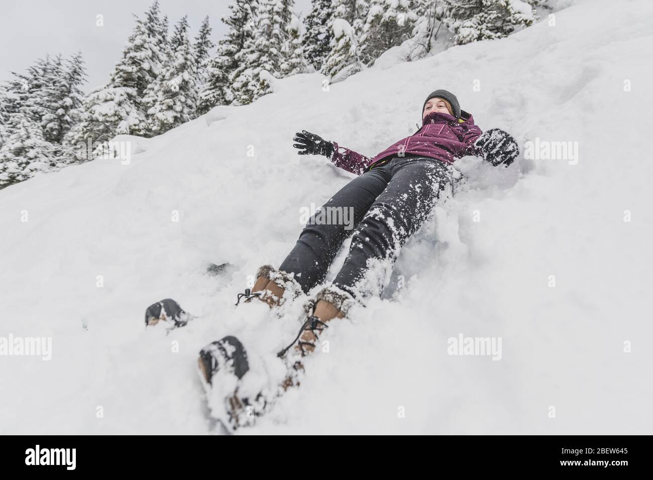 Junge Frau mit Hut schnell in den Schnee hinunter lustige Gesicht gleiten Stockfoto