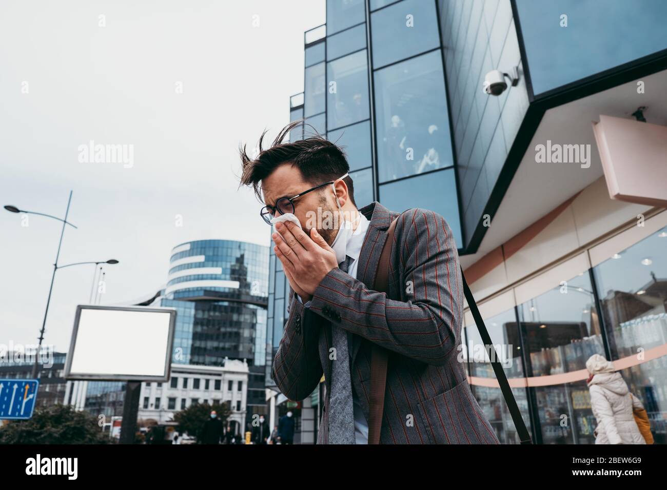Kranker Mann hustet und niest auf der Straße der Stadt. Stockfoto