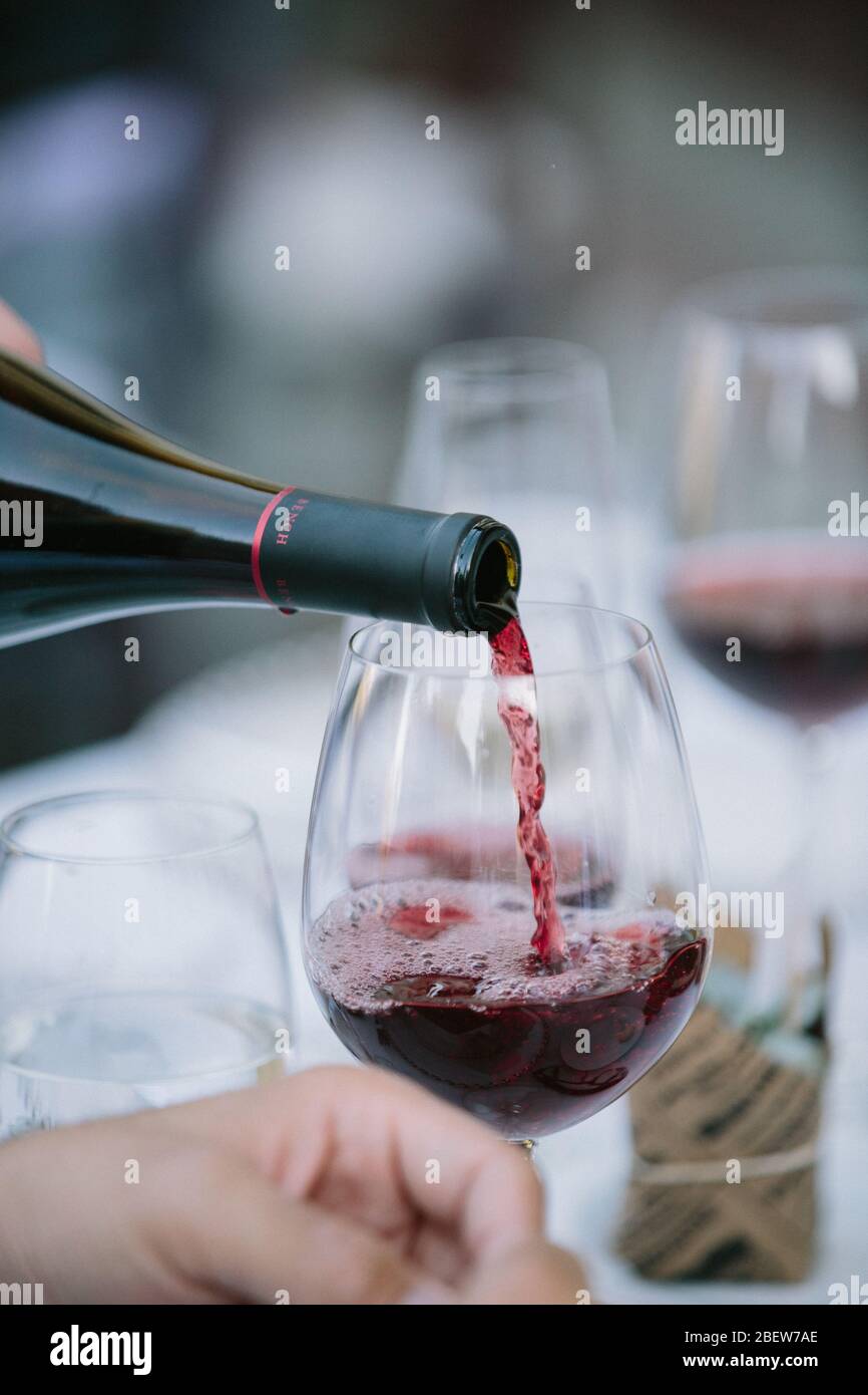 Rotwein wird aus der Flasche in Glaadd gegossen Stockfoto