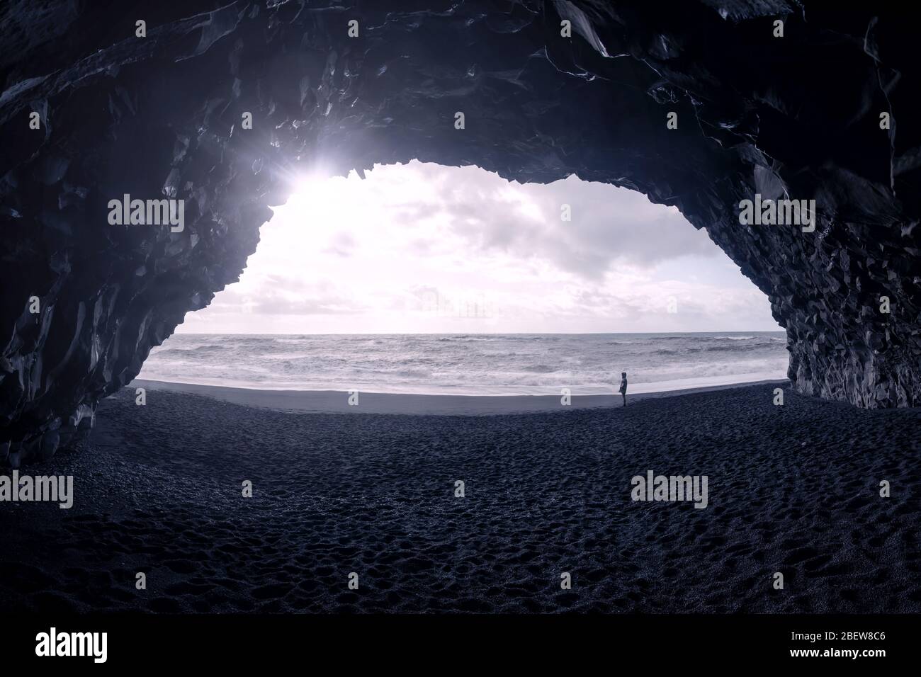 Blick auf den Menschen am Strand bei Sonnenuntergang am Meer von Basalthöhle, Reynisfjara, Island Stockfoto
