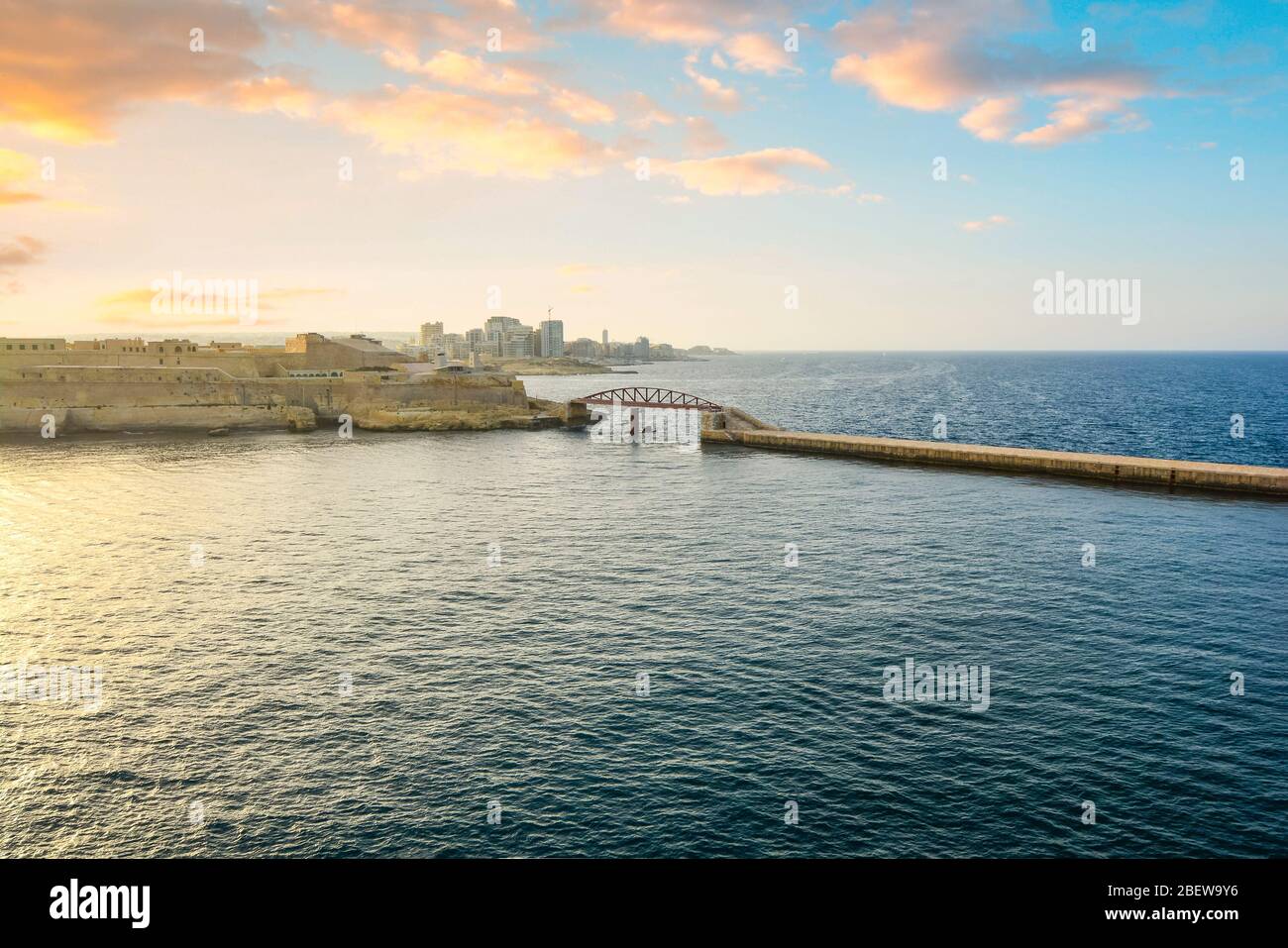 Die St. Elmo Brücke, eine Bogenbrücke unter einem bunten Sonnenuntergang Himmel in der Dämmerung im Valletta Grand Harbour der Mittelmeerinsel Malta. Stockfoto