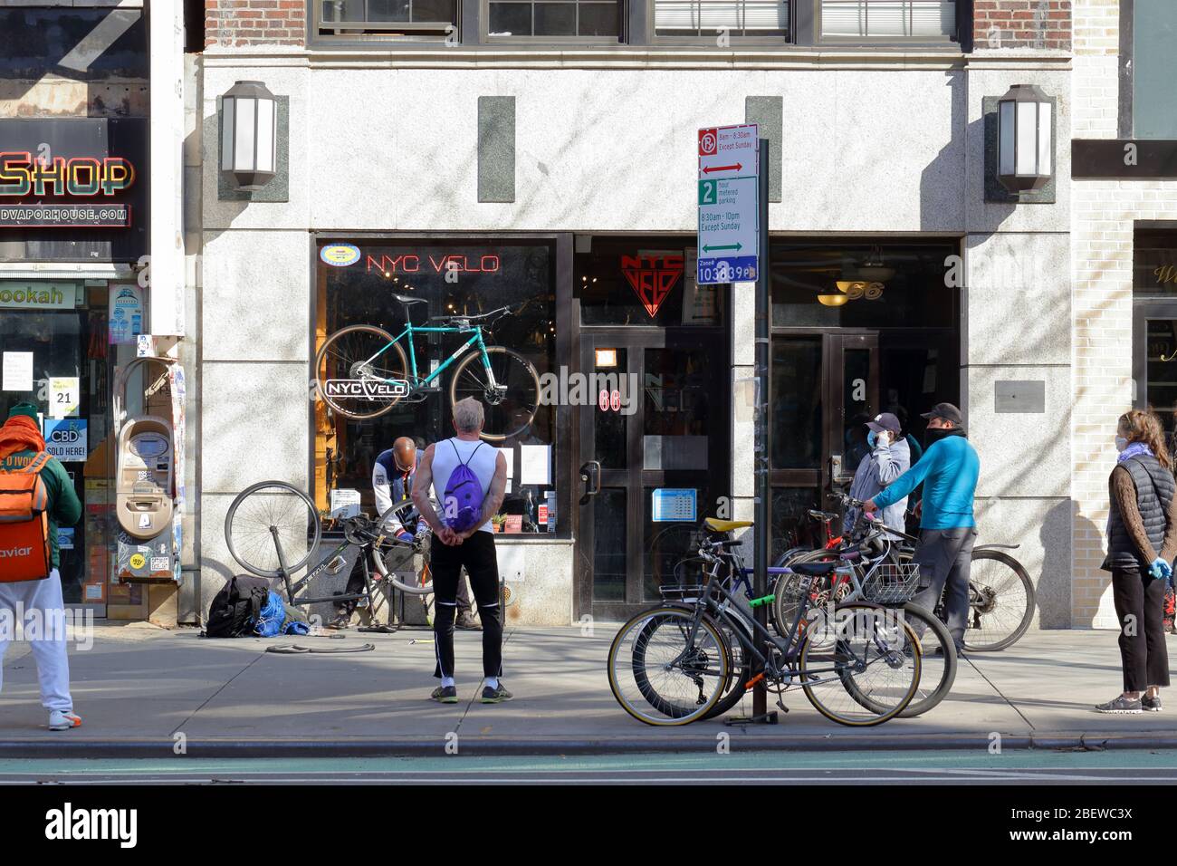 Menschen, die Masken tragen und soziale Distanz, während sie vor einer Fahrradwerkstatt in New York während des Coronavirus warten... WEITERE INFORMATIONEN FINDEN SIE UNTER „VOLLSTÄNDIGE BILDUNTERSCHRIFT“ Stockfoto