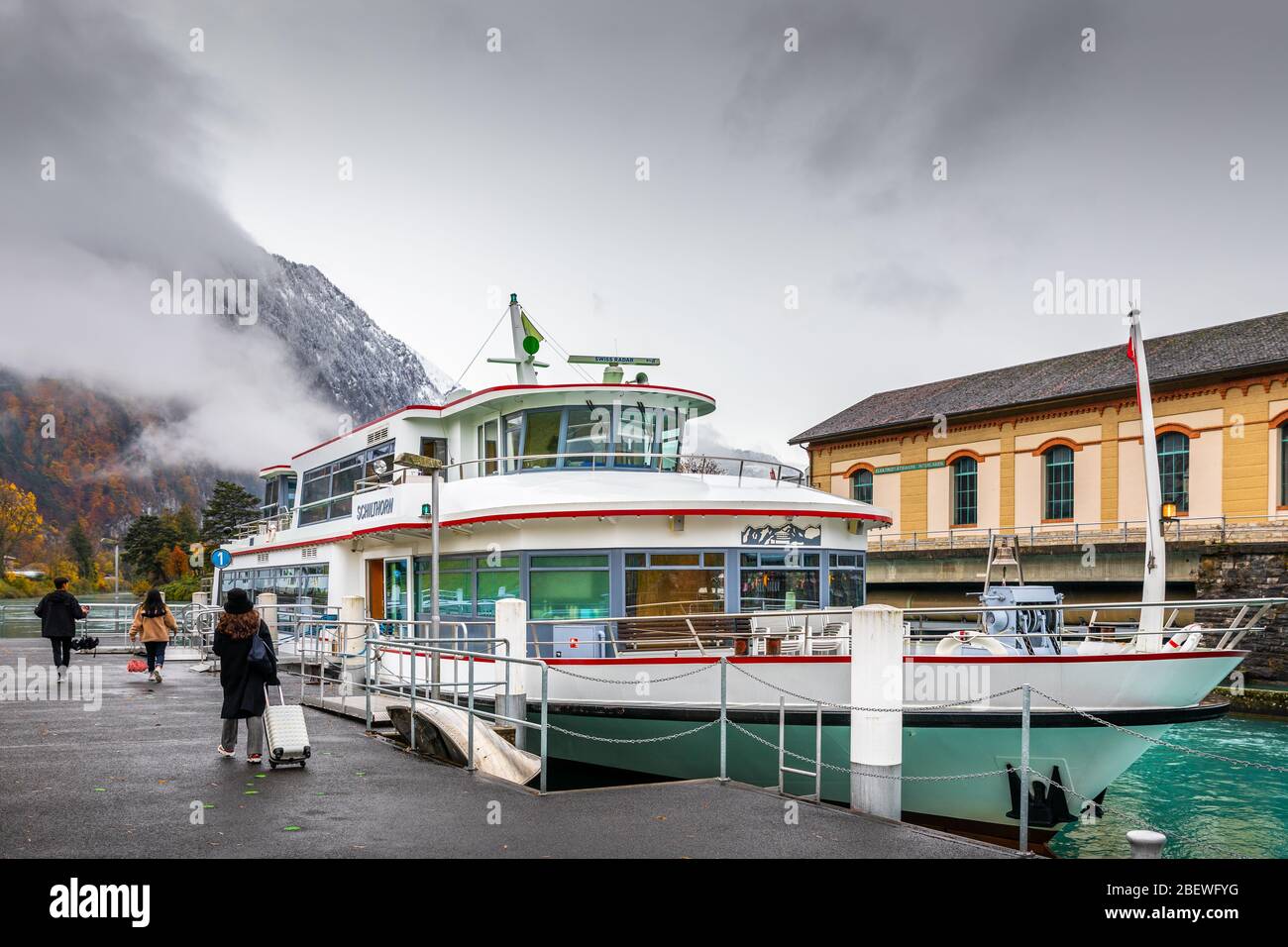 Interlaken, Schweiz - 8. November 2019: Touristen mit Gepäck zu Fuß zum Boot im Hafen von Interlaken West für Thun See Sightseeing. Stockfoto
